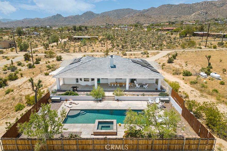 Welcome to resort style living at this gorgeous furnished mezmerizing pool home! Less than 10 minutes from the JTNP, blocks from the village, and surrounded by accessible hiking trails, this stunning modern Mediterranean home has everything you could desire. 4 bedrooms, high ceilings, an open floor plan, updated interior and perfect backyard pool oasis await you on over an acre of land. Walk thru the entry and feel inspired in this bright and stylish single level home. The family room impresses with a wood burning fireplace and open concept kitchen with a peninsula, full suite of built in stainless steel appliances, granite countertops, and an eating nook overlooking the backyard. There are two primary en suites, one featuring a massive jetted tub, separate shower, double sinks, and a walk-in closet! The home also boasts 2 more bedrooms and a full bathroom in addition to a formal dining room (currently in use as a 5th bedroom), pantry, and laundry room. The massive attached garage is easily accessed from inside of the home to make bringing in your groceries a breeze. This home was repainted inside and out including cabinets, has updated appliances and flooring (no more carpet), new electric water heater, PLUS features an owned solar system to keep your electric bill low.



Drop your bags and head straight to the generous backyard where you can sit on the large covered patio with a glass of wine, roast marshmallows on the firepit, experience a soothing sound bath by one of Joshua Tree's many healers and musicians, or serve a fantastic meal. Watch the kids play in the oversized heated in-ground pool until bedtime when you sneak out for a dip in the spa. Beautifully landscaped and fully fenced, you'll only want to leave this oasis to tinker in your giant garage with plenty of space for a workshop or storing your desert toys.



Close to hiking trails and other landmarks like the Joshua Tree National Park, Integratron, Pappy & Harriet's, Pioneertown, JTRC, and popular off roading areas. It is already a highly successful, 5-star short term rental and is perfect for your primary residence, second home, or investment property! Come enjoy your stunning pool and spa in your backyard oasis today.