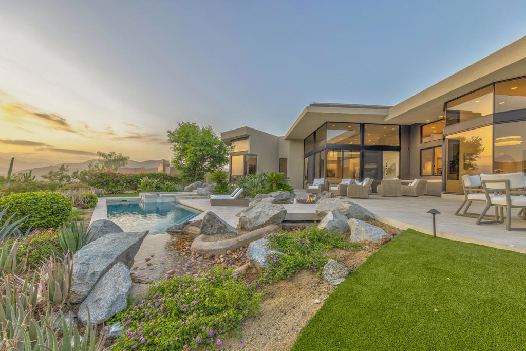 An iconic Guy Dreier design completely transformed by Easton Builders with interiors by Fedderly & Associates. Located in the prestigious Bighorn Golf Club, one of the desert's most exclusive private clubs, this 5,400 sq ft home offers 4 bedrooms, 6 bathrooms, and commanding views of the 9th fairway, picturesque mountain ranges, and city lights from Bighorn's Mountains Course. The primary suite features a private office with courtyard views, luxurious master bath, and newly remodeled steam bath capturing breathtaking vistas. Two interior guest suites occupy the opposite wing, plus a separate-entrance guest house for ultimate privacy. Soaring ceilings, floor-to-ceiling glass, and seamless indoor-outdoor flow create stunning living spaces throughout. Multiple outdoor entertaining areas include a pool and spa, built-in BBQ, reimagined river water feature, and firepit perfect for sunset gatherings. Essentially a brand-new home with stunning cosmetic upgrades, it also features a new roof, completely new plumbing, electrical, HVAC systems, pool equipment. Offered fully furnished and move-in ready.