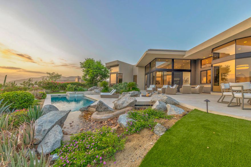 An iconic Guy Dreier design completely transformed by Easton Builders with interiors by Fedderly & Associates. Located in the prestigious Bighorn Golf Club, one of the desert's most exclusive private clubs, this 5,400 sq ft home offers 4 bedrooms, 6 bathrooms, and commanding views of the 9th fairway, picturesque mountain ranges, and city lights from Bighorn's Mountains Course. The primary suite features a private office with courtyard views, luxurious master bath, and newly remodeled steam bath capturing breathtaking vistas. Two interior guest suites occupy the opposite wing, plus a separate-entrance guest house for ultimate privacy. Soaring ceilings, floor-to-ceiling glass, and seamless indoor-outdoor flow create stunning living spaces throughout. Multiple outdoor entertaining areas include a pool and spa, built-in BBQ, reimagined river water feature, and firepit perfect for sunset gatherings. Essentially a brand-new home with stunning cosmetic upgrades, it also features a new roof, completely new plumbing, electrical, HVAC systems, pool equipment. Offered fully furnished and move-in ready.