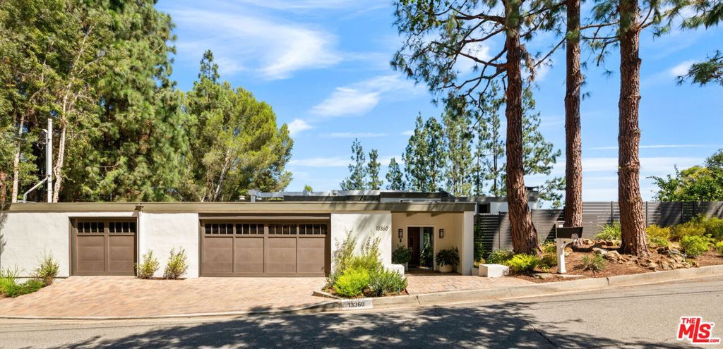 Iconic Architectural Sanctuary in Prime Lower Mandeville Canyon. Brilliant panoramic canyon vistas surround this exceptional, tri-level Matt Kivlin-designed architectural estate, set atop an expansive double lot in one of LA's most coveted enclaves. Blending iconic design with lush natural beauty, this one-of-a-kind residence offers the ultimate live-work-play lifestyle in the heart of Lower Mandeville Canyon. Soaring wood-beamed ceilings, clerestory windows, skylights, and striking fireplaces create warmth and drama throughout the top-level entertaining spaces, where the living room, dining room, family room, and chef's kitchen all flow effortlessly to scenic decks, perfect for lounging, dining, or simply soaking in the serene canyon backdrop. The oversized kitchen is a culinary dream, featuring a center island, stainless steel appliances, solid wood cabinetry, heated floors, and mosaic, granite, and marble finishes. Also on this level: a guest suite with full bath and a powder room. The middle level unfolds to reveal a stunning primary suite with fireplace, sitting area, luxe spa-inspired bath, and oversized closet, plus two guest bedrooms, a shared double-sink bath, a spacious multipurpose studio, and direct access to the spectacular pool/spa patio, grassy play area, and covered entertainment space beneath majestic pine trees. A wine cabinet and dark room add unique flexibility. A spiral staircase leads to the lower level: a bright, inspiring bonus space ideal for a gym, game room, or creative studio, framed by more verdant vistas. Direct access from the large double garage adds ease and functionality. Premium features include: heated flooring in breakfast and primary bath, surround sound inside/out, recessed lighting, custom built-ins, and sophisticated indoor-outdoor flow throughout. This is a rare opportunity to own a bold and timeless piece of architectural art in one of Brentwood's most iconic settings, where nature, design, and privacy unite in perfect harmony.