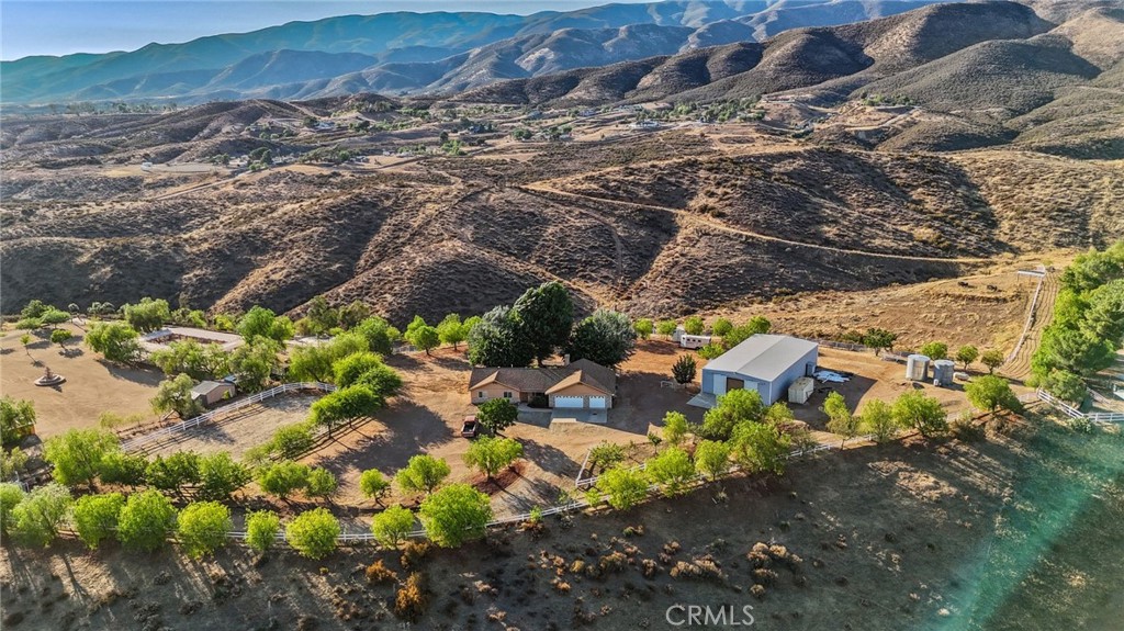 Rare Hilltop, Equestrian Estate with an Industrial-Scale Workshop. This spectacular hilltop estate —comprised of two parcels (APNs: 3214-018-027 & 3214-018-029) totaling over 17.5 acres—combines a spacious custom home, 360-degree panoramic views, a fully permitted industrial-scale workshop, and an adjacent lot, creating a parklike sanctuary with room to grow. A gated, private driveway leads into the approx. 1,800 sq. ft. residence which is designed to maximize privacy while showcasing the stunning natural landscape. It features three bedrooms, three bathrooms, and an office with a private entrance—perfect for working from home. Additional highlights include a 3-car garage, recently serviced septic system, new HVAC, new kitchen appliances, and exterior lighting on the buildings and driveway. The fenced backyard has lush grass, mature shade trees. The crown jewel of this estate is the fully permitted workshop—an incredibly versatile facility ideal for a variety of interests. The building is currently being used as a soundstage and includes two private offices, a bathroom, a spacious second-story storage loft, full 220-amp power, and an oversized RV door. For equestrian enthusiasts, the property features a riding arena, paddock, and ample space for horses to roam. Water resources include two 7,500-gallon storage tanks and a private well. This remarkable property is more than a home—it’s a park, ranch, equestrian facility, hobbyist playground, film location with soundstage, and business opportunity. A rare offering where space, nature, and opportunity come together to support the lifestyle you've been looking for. Saddle up and let’s go. Make your dreams come true.