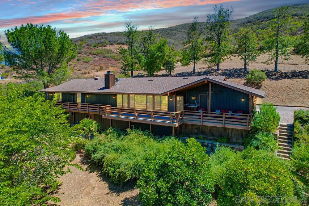 Welcome to your private retreat! Nestled on just over 4 acres, this stunning single-story home offers the perfect blend of comfort, functionality, and breathtaking views. With 3 spacious bedrooms, 2.5 bathrooms, and an additional studio apartment ideal for guests or rental income, this property has something for everyone. Step inside to discover an open-concept layout featuring warm bamboo flooring and soaring wood-beamed ceilings that create an inviting and airy feel. Nearly every room in the house showcases unobstructed mountain views, while a wraparound Trex deck with built-in seating provides the ultimate spot to relax or entertain. The kitchen includes a walk-in pantry and flows seamlessly into the living and dining spaces, making it perfect for entertaining. The primary suite features an updated en-suite bath and tranquil views with french doors leading to the deck. Additional highlights include a separate laundry room, new HVAC and ducting (2023), a newer roof (2017), new water heater, new gutters, and a freshly painted exterior. The property is equipped with leased solar panels, two separate entry gates, and offers ample space to add a pool with incredible views. Enjoy multiple fruit trees including navel and valencia oranges, meyer lemon, plum, apricot, fig, and persimmon. Don’t miss this one-of-a-kind opportunity to own a scenic and versatile property with income potential, privacy, and breathtaking natural beauty!