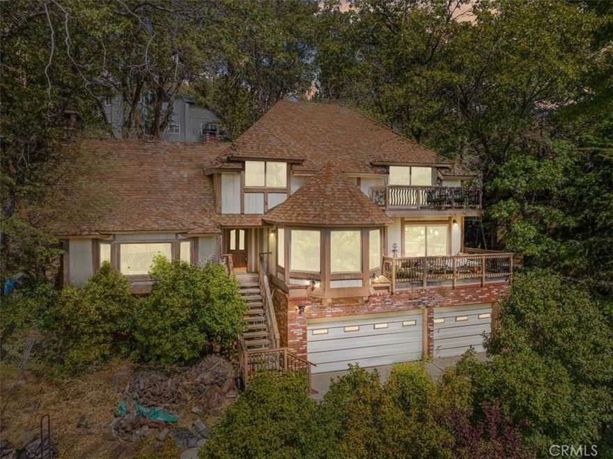 **This home needs some Tender Loving Care, but what an opportunity!** Located just a short distance from the North Bay area of Lake Arrowhead, this property offers private lake rights with a membership to the Arrowhead Lake Association. Enjoy boating, fishing, skiing, and wakeboarding—just a few of the many recreational activities available. The home features three levels of living space. The lower level includes a three-car garage, a laundry room, and a storage area. The main level offers a living room with a cathedral ceiling, picture windows, and a fireplace; a kitchen with a breakfast nook and bay window; a formal dining room with deck access; a massive family room with a fireplace and wet bar; plus a bedroom and bath. The upper level includes a primary suite with an en suite bathroom and access to a viewing deck, along with three additional bedrooms and two hall baths. Other highlights include Knotty Pine paneling, ceiling fans, crown molding, and majestic mountain views.