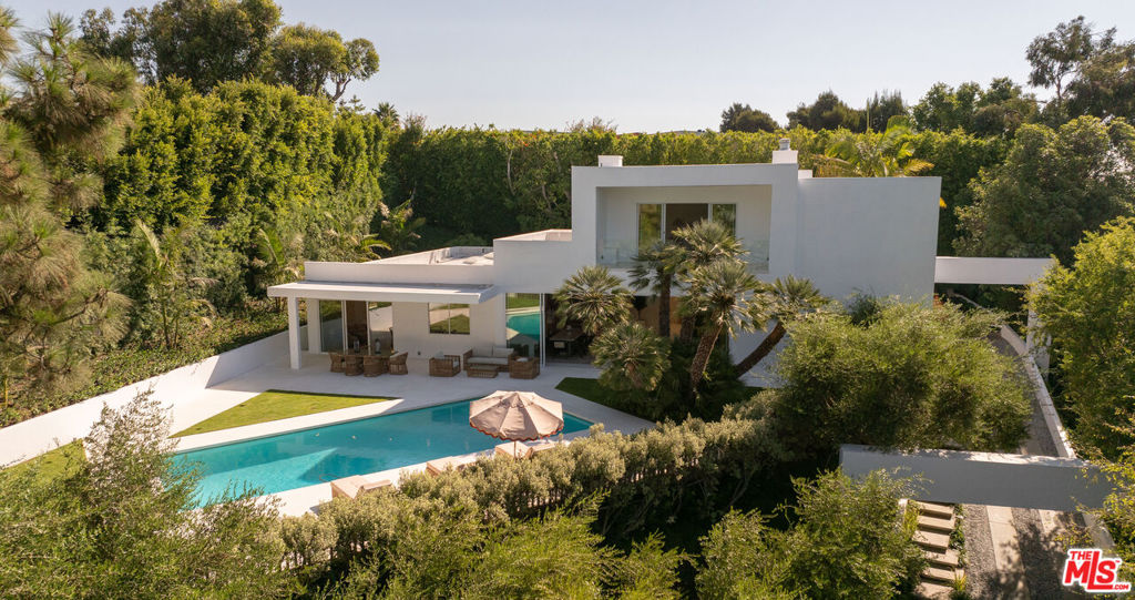 Set behind elegant gates and a long, private driveway, this modern estate exudes sophistication and serenity. Walls of glass showcase lush green views, ensuring total privacy and seclusion. This home offers a tranquil retreat, seamlessly combining contemporary design with natural beauty, just moments from the Heart of Beverly Hills.