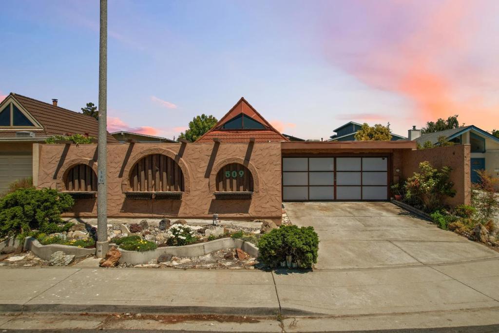 First time on the market since it was originally sold, 509 Crater Lake is a rare opportunity to own a home in this sought-after mid-century neighborhood known for its distinctive adobe-style walls. This architecturally striking 2-bedroom, 2-bath residence was built in 1968 by Bahl Patio Homes and retains its original design elements. The floor plan is thoughtfully laid out, featuring an open kitchen with a loft overhead, vaulted ceilings, and an enclosed causeway connecting the living space to the attached two-car garage. Out front, a private pool is surrounded by mature landscaping, including a tree, and a tranquil pond with a fountain. A bonus flex space can be used as a WFH office, workout room, or even home theater. The home also has multiple outdoor spaces, including a side and back patio accessed from the kitchen, ideal for everyday living or entertaining. With close proximity to major tech campuses, including Apple, as well as dining, shopping, and key commuter routes, this property offers a rare combination of architectural charm, outdoor serenity, and central convenience.