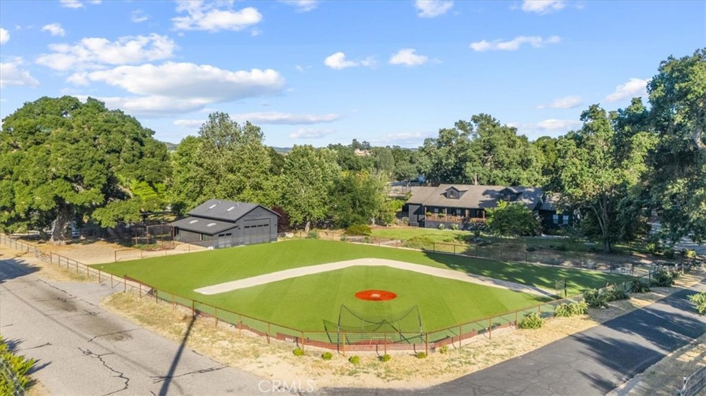 This property knocks it out of the park! Not only does this 2.5-acre retreat feature state-of-the-art baseball training facilities, including a turf practice field, two outdoor batting cages, and an indoor pitching and hitting room, but the real showstopper is the completely remodeled residence at the heart of it all.
The 3,500-square-foot single-level home, offering 4 bedrooms plus an office, showcases a covered front porch overlooking the expansive front yard and practice field. Dual glass and steel front doors open into a formal entry and a spacious great room. Laminate wood floors run throughout, and a modern wood-burning fireplace serves as the centerpiece of the living space.
The stunning chef’s kitchen features a large center island with bar seating, Caesarstone quartz countertops, and a separate wet bar with wine and beverage fridges. Accents of brick and vibrant wallpaper add character and elegance. Nearby, a sophisticated entertaining room includes a sitting area, custom bar, and half bath.
The privately situated primary suite features a gas fireplace, backyard access, an expansive closet, and a spa-like bath with a standalone tub. The indoor laundry room is conveniently located in the same wing. A secondary primary suite with en-suite bath is located on the opposite side of the home, making it ideal for guests.
Step outside to enjoy resort-style amenities including a covered patio with a hot tub, gas firepit, Santa Maria-style BBQ, and a refreshing outdoor shower. Car enthusiasts will appreciate the detached 3-car garage equipped with an EV charger. Additional upgrades include owned solar, dual-zone HVAC, and a tankless water heater.
The impressive 1,620 sq ft barn/workshop is currently used as an indoor baseball training facility with a gym area, but it also offers flexibility to become an ADU, horse barn, or RV garage. The fully fenced turf practice field measures approximately 125' x 170' with 165' to center, 150' to left, and 115' to right. Built with gopher wire beneath the surface, it offers a low-maintenance, pro-style setup perfect for training and play.
Blending luxury living with unmatched versatility and one-of-a-kind baseball amenities, this property is a rare opportunity to live, play, and entertain on a truly extraordinary scale!