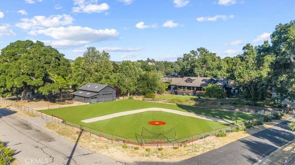 This property knocks it out of the park! Not only does this 2.5-acre retreat feature state-of-the-art baseball training facilities, including a turf practice field, two outdoor batting cages, and an indoor pitching and hitting room, but the real showstopper is the completely remodeled residence at the heart of it all.
The 3,500-square-foot single-level home, offering 4 bedrooms plus an office, showcases a covered front porch overlooking the expansive front yard and practice field. Dual glass and steel front doors open into a formal entry and a spacious great room. Laminate wood floors run throughout, and a modern wood-burning fireplace serves as the centerpiece of the living space.
The stunning chef’s kitchen features a large center island with bar seating, Caesarstone quartz countertops, and a separate wet bar with wine and beverage fridges. Accents of brick and vibrant wallpaper add character and elegance. Nearby, a sophisticated entertaining room includes a sitting area, custom bar, and half bath.
The privately situated primary suite features a gas fireplace, backyard access, an expansive closet, and a spa-like bath with a standalone tub. The indoor laundry room is conveniently located in the same wing. A secondary primary suite with en-suite bath is located on the opposite side of the home, making it ideal for guests.
Step outside to enjoy resort-style amenities including a covered patio with a hot tub, gas firepit, Santa Maria-style BBQ, and a refreshing outdoor shower. Car enthusiasts will appreciate the detached 3-car garage equipped with an EV charger. Additional upgrades include owned solar, dual-zone HVAC, and a tankless water heater.
The impressive 1,620 sq ft barn/workshop is currently used as an indoor baseball training facility with a gym area, but it also offers flexibility to become an ADU, horse barn, or RV garage. The fully fenced turf practice field measures approximately 125' x 170' with 165' to center, 150' to left, and 115' to right. Built with gopher wire beneath the surface, it offers a low-maintenance, pro-style setup perfect for training and play.
Blending luxury living with unmatched versatility and one-of-a-kind baseball amenities, this property is a rare opportunity to live, play, and entertain on a truly extraordinary scale!
