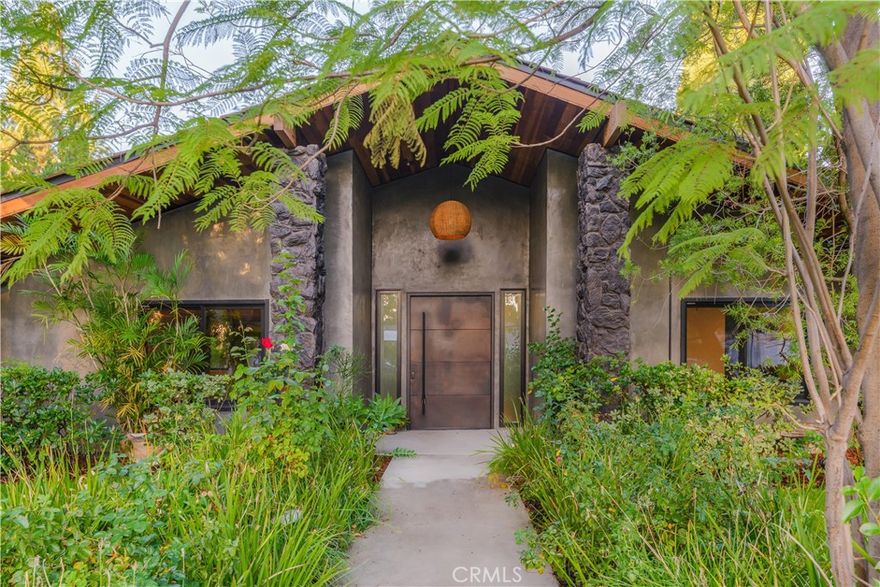 If you’ve ever wished you could live in a resort, this might be your dream home. Inspired by life in Hawaii, 9701 Bothwell Road in the sought-after Devonshire Highlands neighborhood of Northridge offers an unexpected oasis in one of the most desirable areas of the northern San Fernando Valley.



Custom concrete finishes and lava rock accents bring a subtle island aesthetic home. Accordion-style bi-fold doors open to the backyard, where a pool, spa, and tanning ledge sit amid lush tropical foliage. The result is seamless indoor outdoor living that defines the Southern California lifestyle.



Inside, this single-story Northridge luxury home unfolds into multiple living areas, including two family or den spaces separated by an impressive double-sided lava rock fireplace. The open floor plan offers flexibility for dining, a home office, or creative production, with several photo-worthy backdrops ideal for content creators or influencers.



The kitchen features Fisher & Paykel appliances, including dual refrigerators and an induction cooktop. Throughout the home, you’ll find custom woods, designer hardware, and thoughtful finishes. The primary suite feels like a private retreat, with a spa-inspired bath and rich natural materials that create a calm, resort-like experience.



With four total bedrooms (including a secondary suite currently used as a den with its own mini-kitchen and possible future junior ADU) and three and a half custom baths, this is a home unlike any other in the Valley. The property is also fully wheelchair accessible and barrier-free, incorporating significant Universal Design features that make it both functional and inclusive — a rare find among San Fernando Valley luxury homes.



Set within the Devonshire Highlands tract, known for its spacious lots, mature trees, and wide streets, the neighborhood blends a quiet suburban feel with city convenience. Residents enjoy proximity to Porter Ranch shopping and dining, CSUN’s cultural venues, and easy freeway access to Burbank, Studio City, and West Los Angeles. The area’s reputation for long-term ownership and well-maintained properties makes it one of Northridge’s most desirable communities for buyers seeking space, privacy, and enduring value.