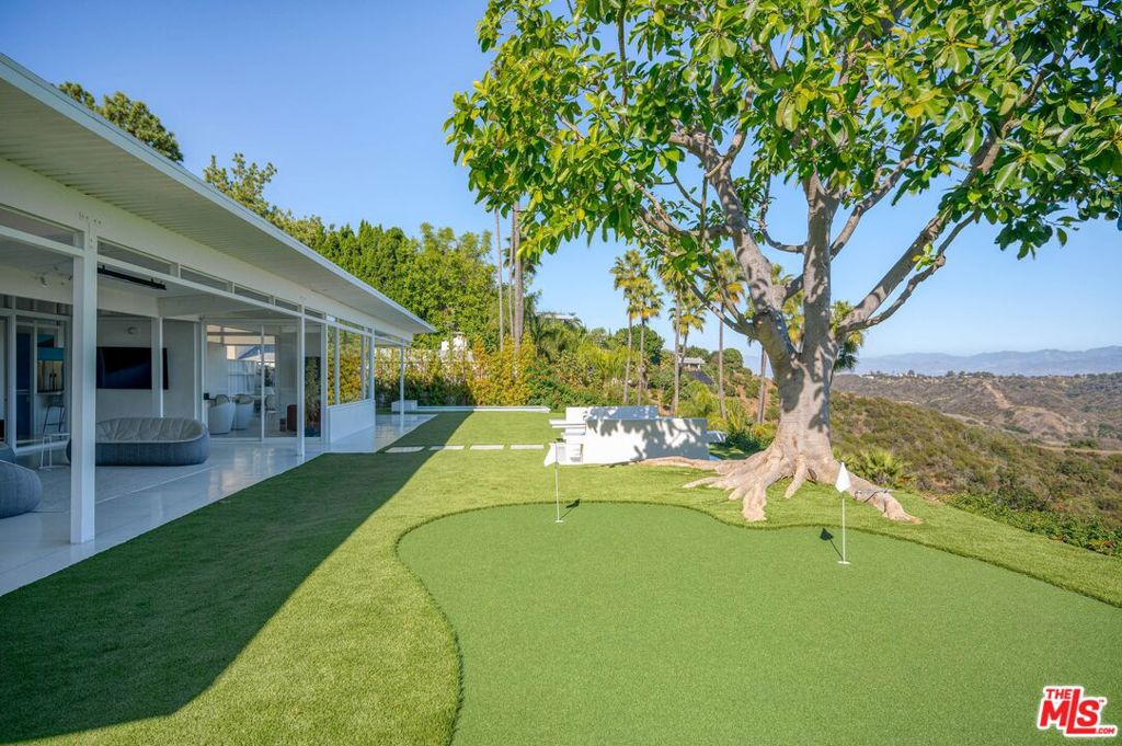 Perched in the hills of Bel Air, 2262 Stradella Road represents a striking revival of architect J.R. Davidson's mid-century vision. First completed in 1958, the residence has been reimagined through a two-year restoration that honors its original character while layering in modern materials, design elements, and smart-home technology. Expansive glass walls dissolve the boundary between indoors and outdoors, showcasing sweeping views of Stone Canyon Reservoir, the Santa Monica Mountains, and the city skyline.Inside, terrazzo floors flow seamlessly through the home, offset by custom wood cabinetry and exposed beams that emphasize its architectural pedigree. The galley-style kitchenequipped with premier appliances and handcrafted cabinetryopens to a dramatic outdoor pavilion designed for all-season entertaining. Retractable glass walls, a fully outfitted second kitchen, and built-in heating create a true extension of the home.The primary suite is secluded for privacy and framed by uninterrupted views, while the spa-inspired baths feature floating slab vanities, switch-glass privacy systems, an infrared sauna, and even a cryotherapy chamber. Outdoors, approximately 1,400 sq. ft. of living space is devoted to relaxation and entertaining, with integrated sound and media systems. A temperature-controlled reflecting pond anchors the grounds, complemented by a private putting green and fire pit perfectly oriented for jetliner views.Plans, soils, and surveys are in place for the addition of an infinity-edge lap pool and ADU, offering future potential for an even more elevated lifestyle.