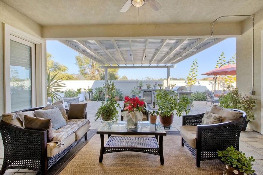 Welcome to this stunning SINGLE-STORY home nestled in the serene and intimate community of Rancho Palomar, a small enclave of just 22 homes at the entrance to the breathtaking San Pasqual Valley. This rare gem offers the perfect blend of privacy, space, and panoramic mountain views, making it a truly special retreat.  Set on a large private lot with ample space between neighbors, this 4-bedroom, 3.5-bathroom residence also includes a versatile flex space that can easily be transformed into a 5th bedroom, offering flexibility for a home office, playroom, or additional bedroom to suit your family’s needs.  Upon entering, you are greeted by an open floor plan that seamlessly connects the living, dining, and kitchen areas. The inviting living room is perfect for relaxing, while the adjoining dining area provides an elegant space for entertaining. Oversized sliding glass doors lead to a covered California room, seamlessly blending indoor and outdoor living to embrace the stunning views and San Diego’s impeccable year-round weather.  The gourmet kitchen is a chef’s dream, featuring modern appliances, abundant counter space, and an oversized island. Whether hosting gatherings or preparing everyday meals, this kitchen is perfect for both entertaining and family time. Its open layout keeps you connected with guests while cooking, making it ideal for socializing and culinary creativity.  The expansive primary suite offers ultimate privacy, complemented by a luxurious en-suite bathroom. For added convenience, this home also includes a second, smaller primary suite with its own en-suite bathroom and walk-in closet—perfect for multi-generational living or guest accommodations.  The remaining two bedrooms are generously sized and versatile, ready to serve as bedrooms, a home office, or a hobby space.  Step outside to the spacious, private backyard, where panoramic mountain views create a serene and tranquil environment. This backyard is perfect for outdoor gatherings or simply relaxing in nature. A built-in BBQ and cozy fire pit add to the charm, making it the ideal spot for entertaining or unwinding under the stars. The large lot offers both privacy and open space, giving you the freedom to create your ideal outdoor oasis.  This home offers the perfect combination of privacy, expansive living space, and modern comfort, all just a short distance from local amenities, parks, schools, and entertainment. Don’t miss the opportunity to own this incredible property and experience the best of Southern California living!