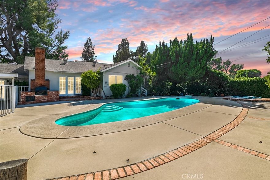 Absolutely gorgeous Porter Ranch pool home with nearly 2,000 sq. ft. of living space on an over 10,000 sq. ft. landscaped lot featuring a pool and RV access. Pride of ownership is evident throughout with hardwood floors, a bright formal dining room with French doors, breakfast bar, and rock fireplace. The spacious family room offers vaulted wood-beamed ceilings, wet bar, French doors, and new laminate flooring. The kitchen includes tiled counters, double oven, cabinetry, and a breakfast nook. The primary suite boasts hardwood floors, ample closets, vanity, and an updated bath, while the secondary bedrooms also feature hardwood floors and ceiling fans. Enjoy the entertainer’s backyard with sparkling pool and spa, large patio, brick BBQ, fruit trees, and covered parking with private entry. Recent upgrades include new roof, windows, recessed lighting, and freshly painted inside and out.