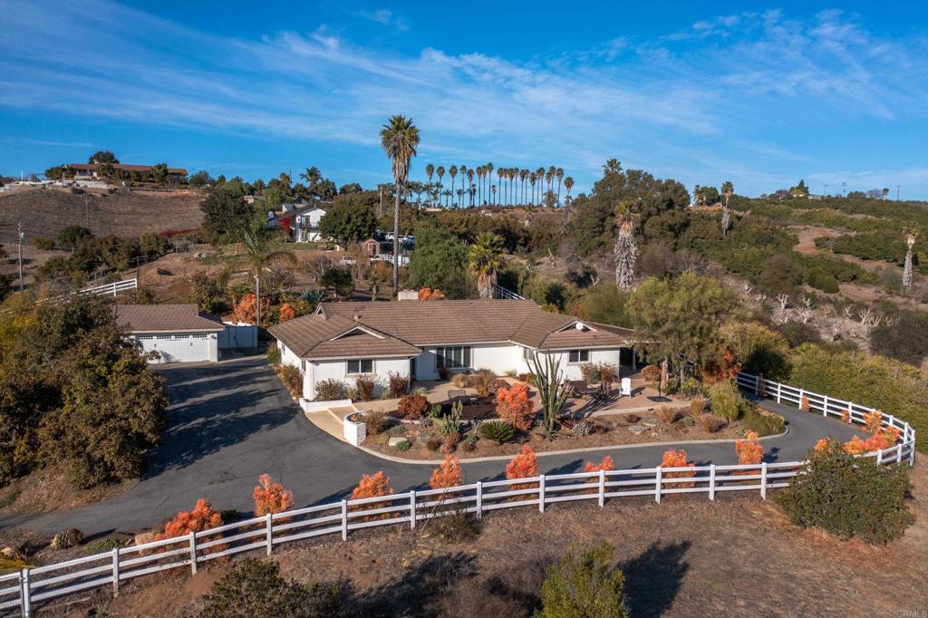 Sweeping panoramic views and peaceful countryside living await at this private, gated, single-story ranch-style home in the hills of Bonsall. Over the past two months, the backyard has been entirely reimagined with terraced landscaping, a new viewing deck, a large grassy area, additional hardscaping, and a custom retaining wall, creating an ideal outdoor space for entertaining or sports. Set on a fully fenced lot, the property offers privacy, open space, and a blend of natural beauty and comfort. Inside, you'll find 3 bedrooms, 3 bathrooms, an expansive kitchen with granite countertops, a walk-in pantry, top-of-the-line appliances, and ample storage. The primary suite includes a large walk-in closet and a recently remodeled bathroom. The home also features newer hardwood floors throughout. The detached garage includes a bonus room or office and a built-in tool shed. The covered patio offers space for alfresco dining, while the grounds include avocado and fruit trees, drought-tolerant landscaping with rare succulents and desert plants, and plenty of room for additional farming or gardening. This is a unique opportunity to enjoy relaxed, scenic living with both charm and functionality.