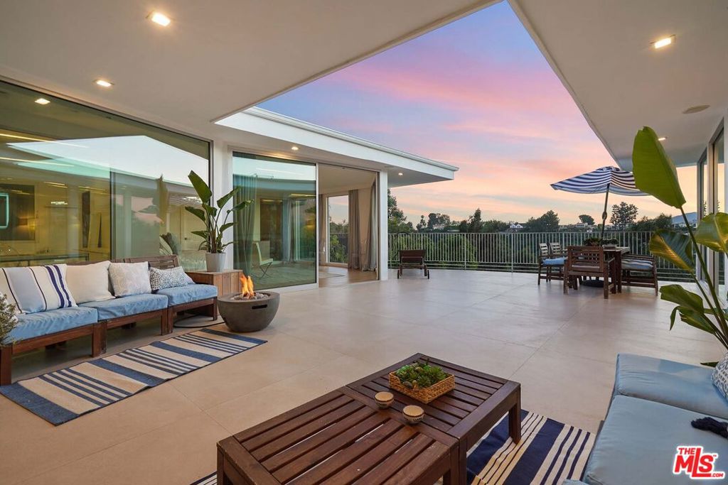 Extensively updated throughout and featuring a floor plan that maximizes indoor-outdoor flow, this quintessential California view home is ideal for entertaining. Guests enjoy beautiful sweeping vistas of treetops, the hills, and city lights through walls of glass that envelop the common spaces. From the rooftop, downtown Los Angeles can also be seen. A frosted glass front door opens to a parlor area highlighted by an artistic niche wall for displaying art pieces. Nearby, the gourmet Pedini-designed kitchen is illuminated by a large skylight overhead and equipped with top-of-the-line Miele appliances including an espresso machine, a sizable waterfall island, and custom cabinetry. Adjacent to the formal dining is the living room with floor-to-ceiling picture windows, decorative fireplace, and sliding glass to the home's central patio. A junior primary has custom closets, sitting area, side garden, and bath with separate rainwater shower and soaking tub. The owner's wing has striking mountain and treetop views, a reeded accent wall, and an en-suite bath with floating dual-sink vanity, smart mirror, oversized aromatic rainwater steam shower with bench, jetted tub, walk-in closet with custom built-ins, and makeup station. Both primary designer closets are also designed by Pedini and imported from Italy. Outside, relax and entertain around the fire pit, serve party guests, barbecue, dine al-fresco, and enjoy gorgeous cotton candy skies during LA's beloved pink hour. This coveted West Gate Bel Air location is tucked away and private yet just moments to freeways, Sunset Boulevard, Westwood, Century City, Beverly Hills, Brentwood, and all the Westside offers.