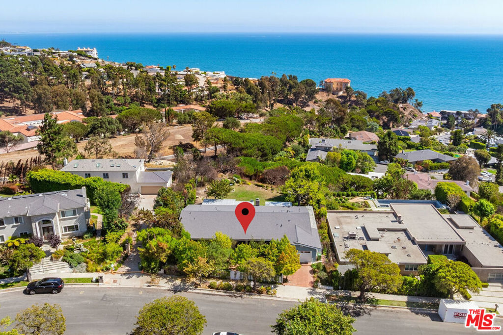 Perched just above the Getty Villa in Pacific Palisades, this Pacific View Estates retreat is now available for the first time EVER! Only moments from Sunset Blvd @ PCH and Gladstones, and just a block to the beach. A classic 60s ranch commands wide frontage and a deep half-acre lot, with an enormous private flat pad in this prime, groomed enclave with underground utilities and wide streets, largely untouched by recent fires. See the sailboats on the Pacific from the house, hear the waves and birdsong carried through the canyons & coastal air, giving a sense of calm and connection to nature, yet so close to town. With close to 3,000 square feet, the 5 bedroom/3.5 bath residence unfolds with classic Mid-Century flow, including a large foyer leading to interconnected open concept public spaces: living room with fireplace, dining room, and family room with a wet bar, each steps away from the wide patio, grassy yard, canyon, and alluring ocean views. A generous kitchen includes a breakfast area and adjacent 5th bedroom/maid's quarters with bath (more ocean views), perfectly positioned for creative, minor floor plan adjustment whether as a den, office, enlarged kitchen, or other use. The private wing of the home offers 4 bedrooms (3 + convertible den) and 2.5 additional baths, including an extensive primary suite with walk-in closet, providing quiet separation from the main living spaces and direct garden access with views. A large, direct access 2-car garage and original circular driveway option (2 curb cuts remain in the broad front yard) complete the offering. Payment of nominal, optional HOA dues to the Pacific View Estates HOA (waived in 2025) provides annual passes to the Getty Villa for residents and guests without reservations. Whether thoughtfully updated or completely reimagined, here is your opportunity to create a legacy estate in one of the Palisades' most coveted enclaves.