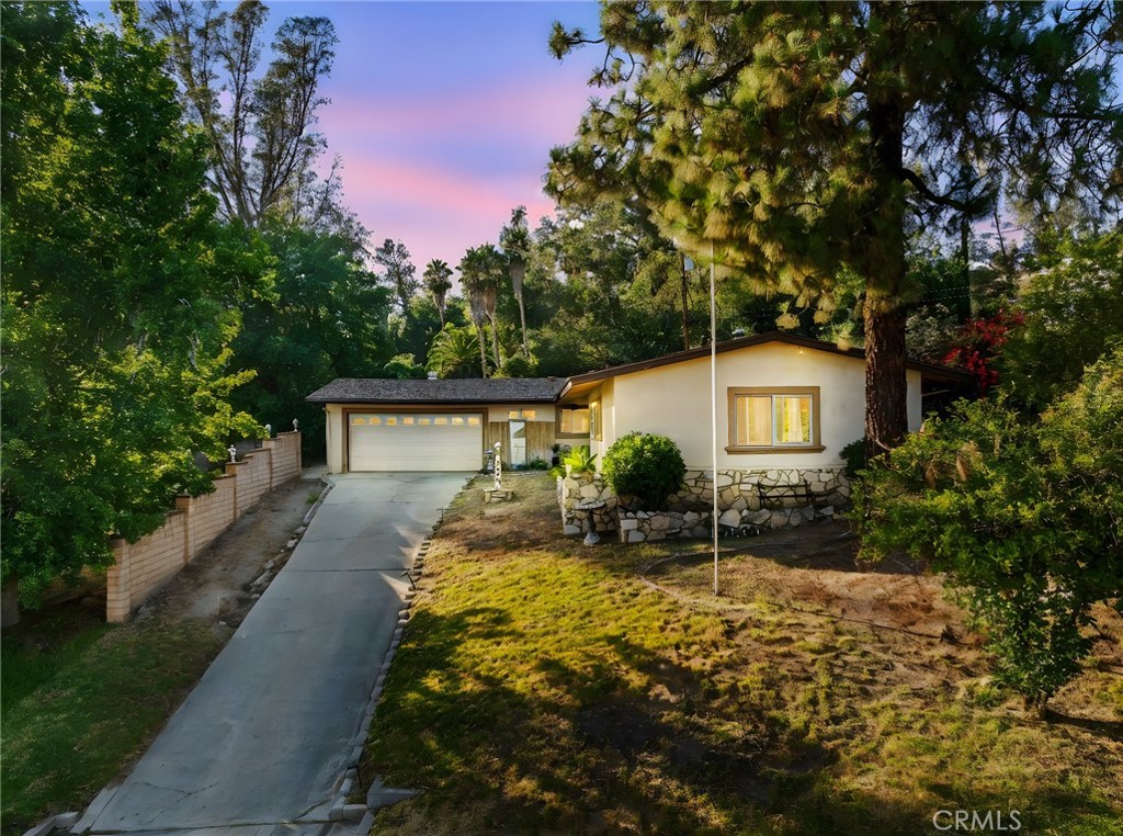 Nestled at the end of a peaceful cul-de-sac, 1850 Belmont Ct offers the perfect combination of privacy, space, and flexible living. This single-story home sits on a spacious 0.3-acre lot surrounded by mature trees and lush landscaping, providing a serene and secluded setting. A charming stone-accented exterior and inviting front entry set the tone for the warmth and character found throughout the home.
Inside, you'll find a beautifully updated kitchen with granite countertops, tile flooring, rich cabinetry, and a breakfast bar that opens into a bright dining area with direct access to the backyard. The cozy living room showcases vaulted wood beam ceilings, a floor-to-ceiling stone fireplace, and large picture windows that flood the space with natural light and capture views of the backyard retreat. The main residence features three generously sized bedrooms and remodeled bathrooms with modern finishes and tile-surround showers.
What truly sets this property apart is the attached ADU with its own private entrance—ideal as a guest suite, in-law quarters, or potential rental income opportunity. Step into the expansive backyard, where a covered patio provides a shaded space for outdoor dining or lounging. With its tranquil setting, functional layout, and added income potential, this home is a rare find in a quiet San Bernardino neighborhood.
