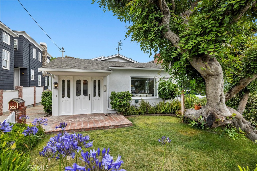 Welcome to this charming home in the heart of the Manhattan Beach Tree Section. With its crisp white exterior, classic brick details, and lush landscaping, this residence blends timeless curb appeal with bright and airy interiors. Inside, natural light pours through oversized windows, highlighting hardwood floors and a coastal-inspired palette throughout the main living spaces. The living room features a white brick fireplace and built-in window bench seating, creating a warm and welcoming atmosphere. The galley-style kitchen offers generous cabinetry, vintage tile countertops, and updated hardware, opening to a cozy breakfast nook and adjacent dining area. The split-level layout includes multiple lounging and entertaining spaces—perfect for game nights, relaxing by the second fireplace, or hosting guests. Upstairs, the vaulted-ceiling primary bedroom opens to a private balcony with treetop views. Additional highlights include a dedicated laundry area, spacious downstairs den, and charming built-ins throughout. Situated on a 4,803 SF lot, this 1,972 SF home sits on a quiet, sought-after street just blocks from award-winning schools, Sand Dune Park, and the beach. A rare opportunity to enjoy the best of the Manhattan Beach lifestyle.
