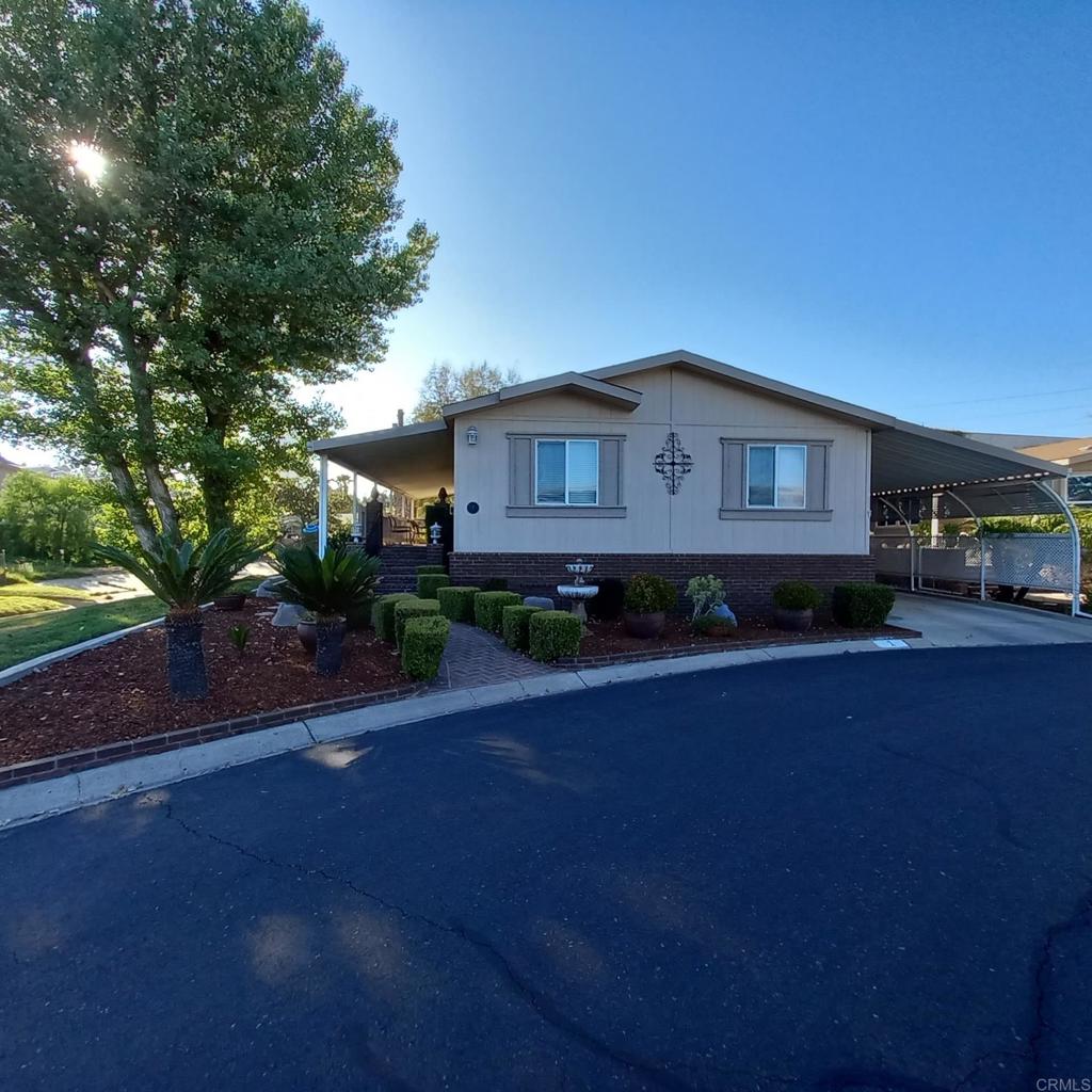 Welcome to RANCHO ESCONDIDO a land owned, no space rent, manufactured home community. Photos to come WED 8-20 GREAT 3 BEDROOM FLOOR PLAN WITH LOTS OF CURB APPEAL! Custom brick walkway and front stairs at main entry. A corner lot with the homes orientation over looking the green belt. Lot's of windows to enjoy the view along with a large covered deck. The primary suite is located on the opposite side of the home from the other 2 bedrooms with the Kitchen, dining room, living room and laundry room in between. The primary bedroom boasts a large walk in closet and a roomy ensuite. Big kitchen has a large island with seating and a real butcher block space at one end. 1st time on the market, lovingly kept by original owner. RANCHO ESCONDIDO has many amenities and social activities, 2 pools, 2 club houses, a spa, a workout room, card and billiard room and a dog park and more. Come take a tour TODAY, you'll be happy you did! Located in N Escondido convenient to all.