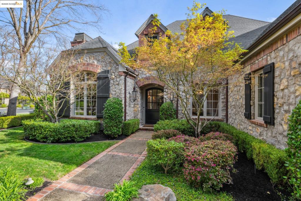 Located in Lafayette’s prestigious Hidden Oaks neighborhood, this European-inspired estate impressively blends Tudor and French Country elements including stone, brick, & stucco siding and a steeply pitched roof with gable windows. The home is surrounded by meticulously landscaped grounds. Inside, soaring ceilings and abundant natural light highlight the refined craftsmanship throughout. The grand foyer leads to an open-concept living space anchored by a grand fireplace, double height ceilings and bi-fold doors. The recently updated chef’s kitchen is equipped with a Viking range, built-in refrigerator, custom cabinetry, and central island. The gorgeous rear yard features a swimming pool & spa, covered patio lounge, lawn, built-in grill, firepit, mature landscaping, & multiple seating areas. Two separate garages provide ample storage and parking (the 1-car garage is poised for use as a home gym or detached office). The home is situated in a quiet cul-de-sac setting just minutes from top-rated schools, downtown Lafayette, and freeway access.