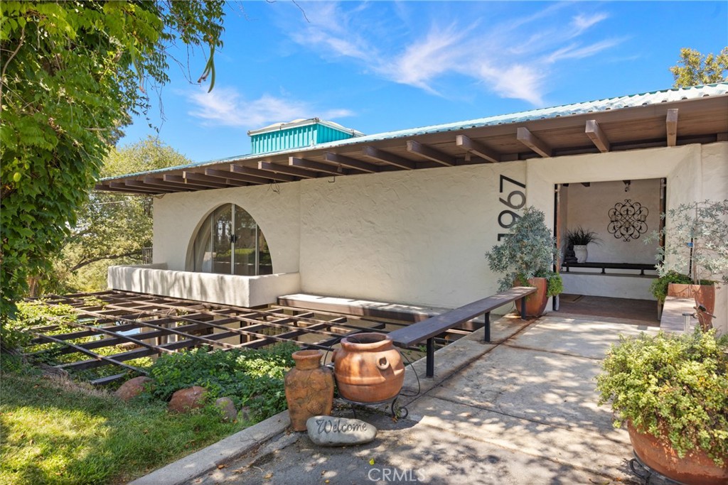 This one-of-a-kind property feels like a world of its own—peaceful, private, and just minutes from town. Set on 5.69 acres with approximately 600 feet of creek frontage along Butte Creek, it offers a rare mix of natural beauty, thoughtful design, and timeless character. A gated entrance leads to a circular drive, ornamental fountain, and tranquil koi pond that set the tone for what’s inside. The main home features five bedrooms and four bathrooms, with hand-carved wood doors, wood-beamed ceilings, architectural arches, and a blend of brick and tile flooring. The split floor plan includes built-ins throughout, multiple terraces, and large picture windows that frame views of the grounds, treetops, pool, and even the Sutter Buttes in the distance. Enjoy morning coffee or evening wine from one of the many balconies, where the sound of Butte Creek drifts through the trees. The pool and hot tub are tucked into beautifully landscaped surroundings, giving the outdoor space a garden-like feel. There's also a private beach area right on the creek—perfect for hosting or unwinding. The remodeled guest quarters now feature a full kitchen, full bathroom, living area, private entrance, and a fenced yard, offering complete flexibility for guests or extended stays. It also includes a loft, living area, and a wood-burning fireplace. Other highlights include a detached two-car garage, owned solar, pressure tank and generator for the well, a workshop area, fruit trees, a small orchard, and a protected wildlife preserve just across the creek that ensures privacy and open views for years to come. Originally built by Gene Henning, the home reflects craftsmanship and detail at every turn. Whether you're entertaining, relaxing, or simply enjoying the peaceful setting, this property offers the feeling of a private retreat—without giving up convenience.