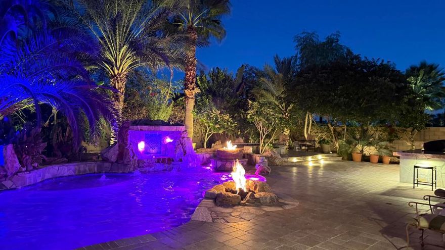 Located in the gated community of Desert River Estates, this furnished 4 bedroom, 4 bath single-level home offers approx. 3,468 sq ft of living space on a rare 21,780 sq ft (approx. 1/2 acre) lot with exceptional privacy and no homes behind you. Ideally positioned between Indio and La Quinta and located within about a mile of the Coachella and Stagecoach festival grounds, the home blends comfort, scale and location in a way that works beautifully as a primary residence, desert retreat or entertainer's getaway. The east-facing orientation minimizes afternoon heat and creates a softer, more enjoyable year-round outdoor environment. The expansive lot includes desert landscaping, a 3-car garage and generous behind-the-wall parking suitable for additional vehicles or an RV, provided it remains screened from street view.The backyard is the heart of the property a true resort environment designed by a professional pool builder as his personal showpiece. The custom pool and spa feature multiple waterfalls, fire elements, bubblers, a dedicated swim-in-place system powered by multiple pumps, a rare in-floor self-cleaning system and extensive LED lighting that transforms the space at night. In addition to a traditional heater, the pool includes a heat-pump cooling system that keeps water at a refreshing temperature during the hot summer months. Outdoor living expands across a large covered patio with ceiling fans, a built-in BBQ/outdoor kitchen, multiple lounging zones, mature date palms, lush landscaping with accent lighting and a private putting green near the gated parking area.Inside, the home offers a spacious great room with fireplace that opens to an island kitchen, creating the ideal hub for gatherings. Three ensuite guest bedrooms are located on one side of the home, while the private primary suite sits on the opposite side with a soaking tub, walk-in shower, dual vanities, a large walk-in closet and direct access to the rear patio and pool. Desert River Estates is known for its quiet elegance, wide streets, beautifully maintained landscaping and all half-acre lots, with limited turnover. Other amenities, putting green, Automatic Gate for behind the wall parking, Outdoor Kitchen with Barbecue and Pellet Smoker.For buyers seeking a refined desert lifestyle, this home delivers space, privacy, craftsmanship and a resort-caliber backyard rarely found at this price point, all close to dining, golf, shopping and the valley's premier events.