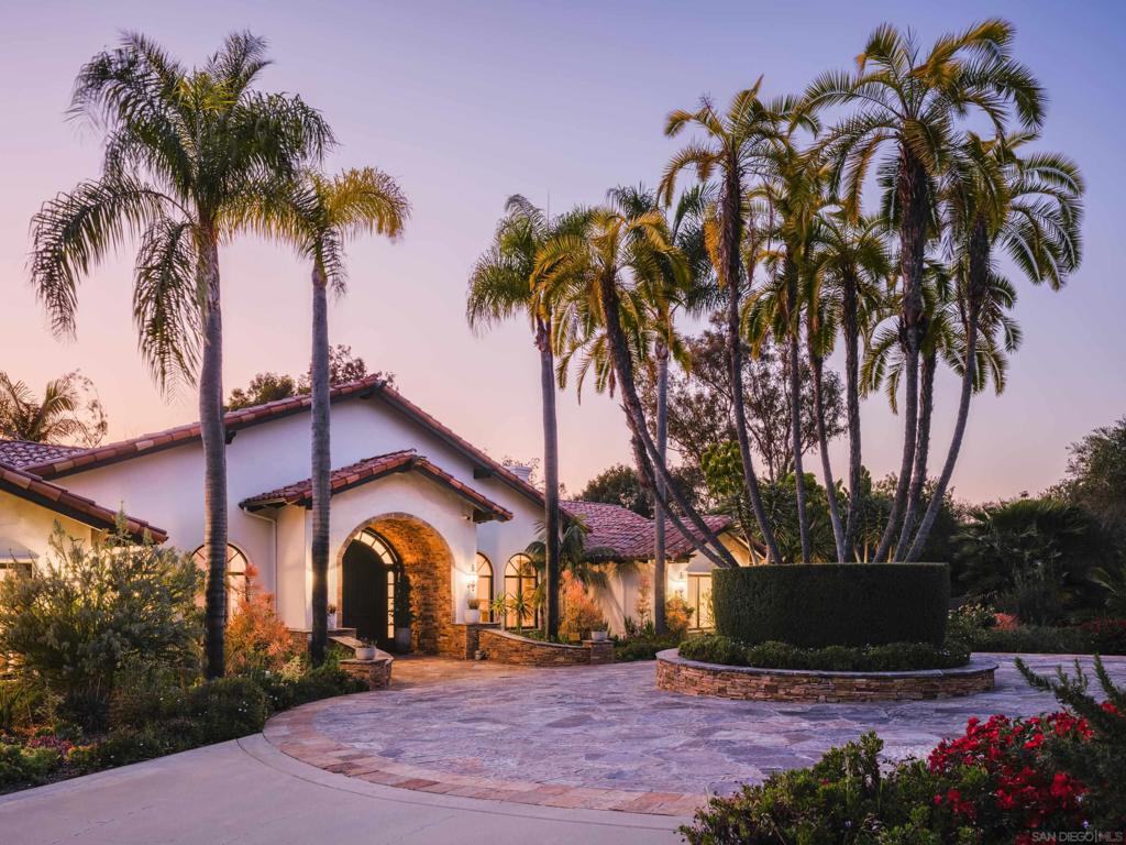 Nestled behind gates on one of the most sought-after streets in the prestigious West Covenant of Rancho Santa Fe, this reimagined single-level Modern Mediterranean estate offers timeless elegance with contemporary updates. Freshly painted inside and out, the home features new herringbone wood flooring, designer lighting, and refined touches throughout. The floor plan is thoughtfully designed, featuring a private primary suite, while a separate wing accommodates flexible secondary bedrooms ideal for family or guests. A dedicated office or library provides a quiet and functional work-from-home environment. Formal living and dining rooms create a refined ambiance, while the heart of the home lies in the open-concept family room that flows seamlessly outdoors and into a gourmet kitchen outfitted with high-end appliances, custom cabinetry, and an inviting eat-in breakfast nook. A fully detached guest house offers incredible functionality, making it ideal for visitors. The resort-style backyard is a private sanctuary, complete with a pool and spa, an outdoor shower, and an expansive covered veranda featuring a fireplace, BBQ, lounge seating area, and al fresco dining. Down below, discover a large grassy area ideal for children, pets, or even the addition of a pickleball court. Lush landscaping, a spacious motor court, and a four-car garage provide ample parking and storage for car collectors and entertainers alike.