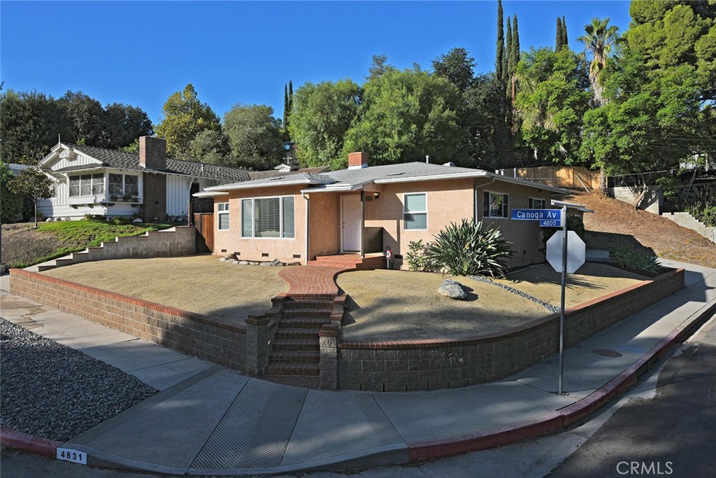 Across from Woodland Hills Country Club, this one-story midcentury residence combines privacy, craftsmanship, and convenience in the coveted south-of-Ventura neighborhood. Fully remodeled and expanded, the home sits on a quiet corner lot less than a mile from Ventura Blvd and minutes from Warner Center. 
 — Light hardwood floors and dual-pane windows create a calm, continuous interior anchored by a gourmet kitchen finished in speckled granite with solid-oak cabinetry and pullout shelving. Lighting comes from five controllable sources: dimmable hidden rope lighting, task lighting over sink and display cabinets, under-counter perimeter lights, ceiling fixtures, and a spotlight above the granite breakfast counter. An ornamental glass door separates the entertainment area from the private wing. 
 — At the end of the hall, a Japanese-style spa serves as the home’s centerpiece: steam system, karaoke audio, deep soaking tub, Calacatta Gold marble walls and baseboards, Breccia Onicata marble surfaces, Robern mirrored cabinets with a fog-free center mirror, and heated towel rack. The master suite features a private full bath with a Kohler Greek soaking tub, a granite countertop and baseboards, Grohe fixtures, a custom closet, and direct access to a secluded patio through a glass slider. 
 — Three separate garages form a practical extension of the living space: a north-facing two-car garage with custom cabinetry and dropped lighting, an adjacent finished single bay with separate doors, and a 100-sq-ft finished motorcycle garage with reinforced floor, full-width ramp, bright lighting, and power outlets—adaptable for workshop or storage. Combined indoor and driveway parking accommodates eight vehicles, including two motorcycles.
The grounds follow a low-maintenance xeriscape of decomposed granite, river stone, and succulents, with a retaining wall leading to undeveloped hillside in the back yard. Upgrades include L-copper plumbing, seismic retrofit, Cat-5 cabling, tankless water heater, central air, and security system. 
 — Trader Joe’s and Whole Foods are roughly 0.9 miles away; Kaiser Permanente less than two miles; UCLA Health, Costco, and Home Depot less than three. A thoughtful home for those who value function, subtlety, and enduring design.