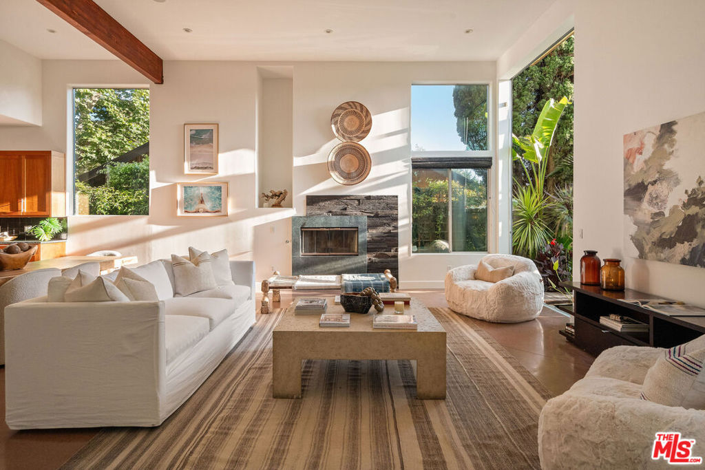 Tucked into the highly sought-after Silver Triangle, this residence is a true Venice sanctuary. Soulful and inviting, it blends warmth, thoughtful design, and ease for a lifestyle that feels both elevated and grounded. Natural light pours across polished concrete floors, where a dramatic reclaimed ebony wood fireplace anchors the open living space with character and calm. A custom green wall garden graces the entryway, while a 14-foot disappearing glass wall extends the home to a private front yard oasis with a water garden and gentle fountain that creates a constant soundtrack of serenity. Evenings unfold effortlessly, whether gathered around the fire pit at sunset, relaxing by the tranquil lava rock water feature, sharing a meal under the stars, or simply exhaling into the quiet of your own retreat. At the heart of the home, the chef's kitchen balances beauty and function with soapstone counters, premium appliances, purified water on tap, and a central island designed to bring people together. Upstairs, Brazilian cherry wood floors lead to spacious guest suites with spa-inspired baths, while the penthouse-style primary suite offers its own private refuge complete with a fireplace, soaking tub, terrace, and oversized walk-in closet. A rooftop deck crowns the home, capturing ocean breezes by day and sparkling city lights by night. When you are ready to step out, Abbot Kinney's renowned dining, the historic canals, the marina, and the beach are all just moments away, offering everything that makes Venice living extraordinary.