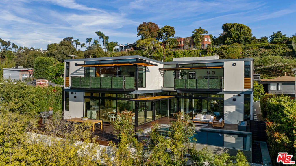 Discover a once-in-a-lifetime opportunity to own a masterwork architectural designed by the late Ray Kappe, FAIA, one of America's most pre-eminent and internationally revered architects. This sun-drenched Modernist home offers exceptional volume, with walls of glass that create a seamless flow between the expansive living, dining, and great rooms and the sparkling pool, all framed by breathtaking Amalfi Rim canyon views. Floating staircase leads to romantic, ocean view, primary suite aerie. Chef's kitchen with Miele and Wolf appliances, Arabescato waterfall island, and Walker Zanger finishes. Second floor surround sound screening room. Four ensuite bedrooms up, downstairs fifth bedroom doubles as guest suite or spacious light-filled office. Floor-to-ceiling glass wine wall cabinet. Control 4 home automation. SPORT COURT. Three-car garage with four additional parking spaces on the property. Street-to-street lot with direct access to Entrada, one block away from a rejuvenating morning workout at the Santa Monica Stairs. A rare and perfected example of Ray Kappe's celebrated modern design with blue water views overlooking cherished Santa Monica Canyon.