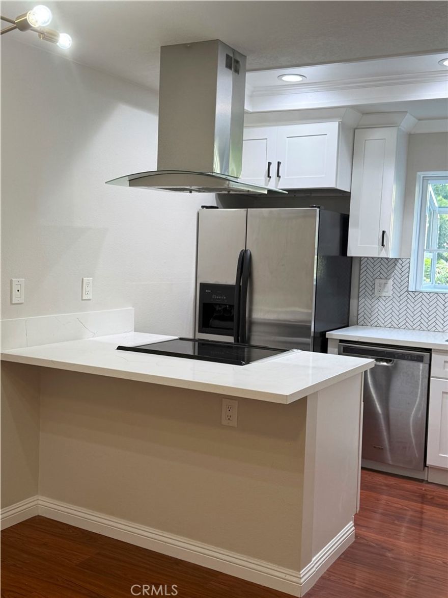 Nestled alongside a peaceful stream this home offers a private and tranquil setting, Newly installed windows and blind elevate the overall comfort and appearance of the space.The kitchen has been upgraded with white quartz counters, refreshed cabinetry, elegant herringbone tile backsplash, and a stainless range hood for a clean, modern look. Recessed lighting and laminate flooring run throughout the main living areas, adding warmth and functionality. The bathroom features a shower with a tub combo and a spacious walk-in closet. Conveniently located near shopping, dining, and freeways. Community amenities include a pool, spa, and tennis courts.