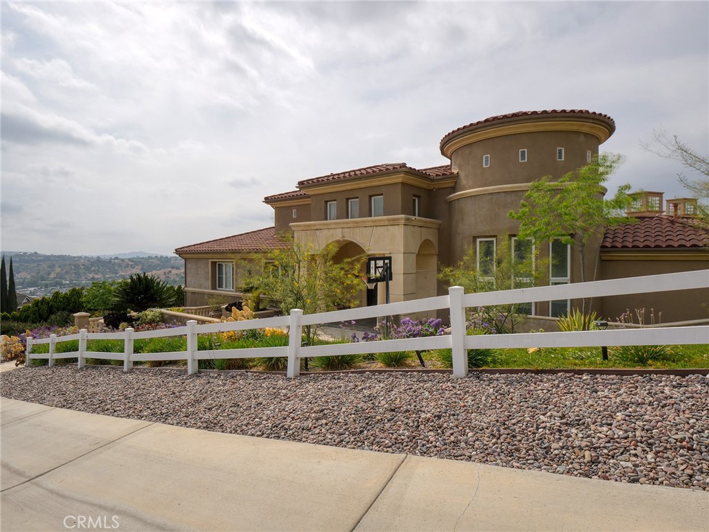 Step into an open view of luxury living at its finest at 22189 Rim Fire Lane, nestled in the coveted 24-hour guard-gated community of The Country in Diamond Bar. This breathtaking custom estate offers unparalleled craftsmanship, stunning views, and an entertainer’s dream indoor-outdoor lifestyle.
With over 6,352 square feet on title and original plan of thoughtfully designed living space on a private 1.03-acre lot, however, it was approx. 6700 SF per original builder, this 5-bedroom, 6-bathroom residence features two full primary suites—one on the main entry level and another on the lower garage level—perfect for multigenerational living or guest privacy. In addition to the bedroom suites, there is a large executive office, multiple entertaining areas, and even a bonus loft with wine cellar.
Main Level Elegance
Upon entry, you’re welcomed by soaring ceilings, dual columns, wrought iron double doors, and a grand formal living area with rich hardwood floors, vaulted wood-beamed ceilings, and a piano lounge. The main level includes the primary master suite with two walk-in closets and a spa-style bath, plus two junior suites, a generous office, and expansive living and dining areas that open to a large balcony with sweeping canyon views.
Chef’s Kitchen Perfection
The gourmet kitchen is anchored by a massive granite island with bar seating and surrounded by warm cherry wood cabinetry. High-end appliances include a refrigerator, professional-grade stainless steel range with double ovens, commercial range hood, and double wall ovens. A dining space and open family room make this the heart of the home.
Lower Level Living
The garage level offers a second master suite, another bedroom with a bath just across the hall, ideal for in-laws, staff, or guests. This level also includes a family room, bonus loft, and access to the patio and resort-style backyard featuring a sparkling infinity-edge pool and spa, all framed by lush landscaping and endless views.
Additional Highlights:
Most furniture included (excluding Steinway piano & two Hermes sofa sets with Chairs, one set downstairs in FR, one set upstairs in LR)
Large balcony and covered patio on both levels
Private driveway leading to 3 car garage on lower level.