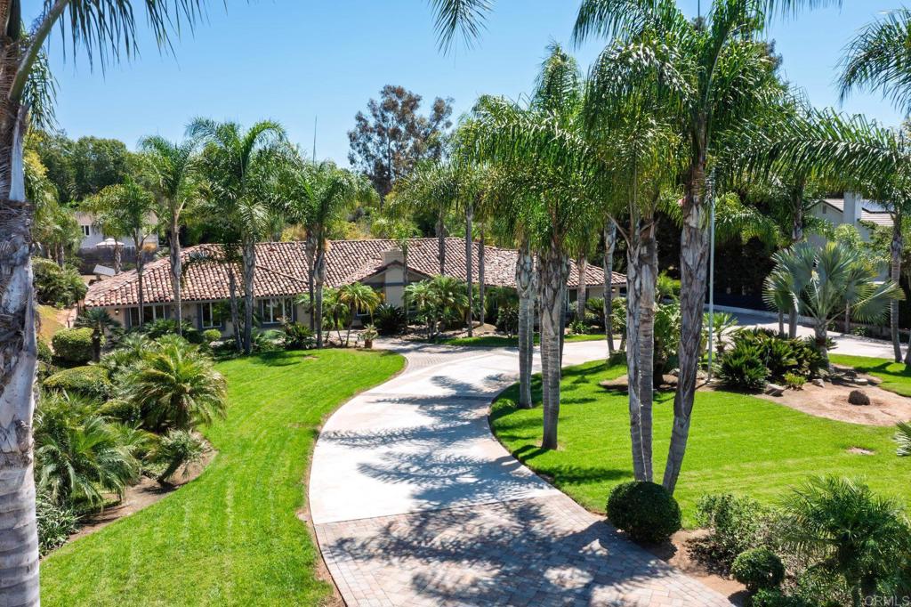 Welcome to this stunning single-story estate on one of Vista’s most sought-after streets set on nearly an acre (.95) with a circular driveway, and a private automatic gate leading to the saltwater pool and huge backyard. This 4-bedroom, 3.5-bathroom home offers exceptional privacy, space, and luxury. A 3-car garage with a convenient half bath, solar, well, whole house fan, and water filtration system add to the home’s functionality and efficiency. Plenty of space is available for an ADU, RV, or recreational toys. Step through the custom double front doors into a bright and open floor plan designed for both entertaining and everyday living. The formal dining room features built-in display cabinetry, while the living room offers a cozy fireplace. The spacious family room boasts vaulted ceilings, skylights, track lighting, a ceiling fan, a fireplace, and a wet bar with a refrigerator. The chef’s kitchen is beautifully appointed with Dacor double ovens, a Sub-Zero refrigerator, an ice maker, a Viking cooktop on the center island, a breakfast nook and a garden window overlooking the sparkling saltwater pool and backyard. The primary suite is a true retreat with two closets, a fireplace, and direct access to the backyard. The spa-like primary bathroom includes a separate shower and soaking tub, Toto toilet and bidet, and views of the private atrium. Additional bedrooms are complete with ceiling fans, while the laundry room includes a utility sink. Upgrades such as stone flooring, plantation shutters, crown molding, soft fit ceilings, retractable screen doors, automatic window shades, and recessed lighting complement the home’s timeless style. Mature landscaping with gorgeous palm trees surrounds this one-of-a-kind estate, creating a tranquil and private setting. A true jewel in Vista, rarely available and impossible to duplicate.