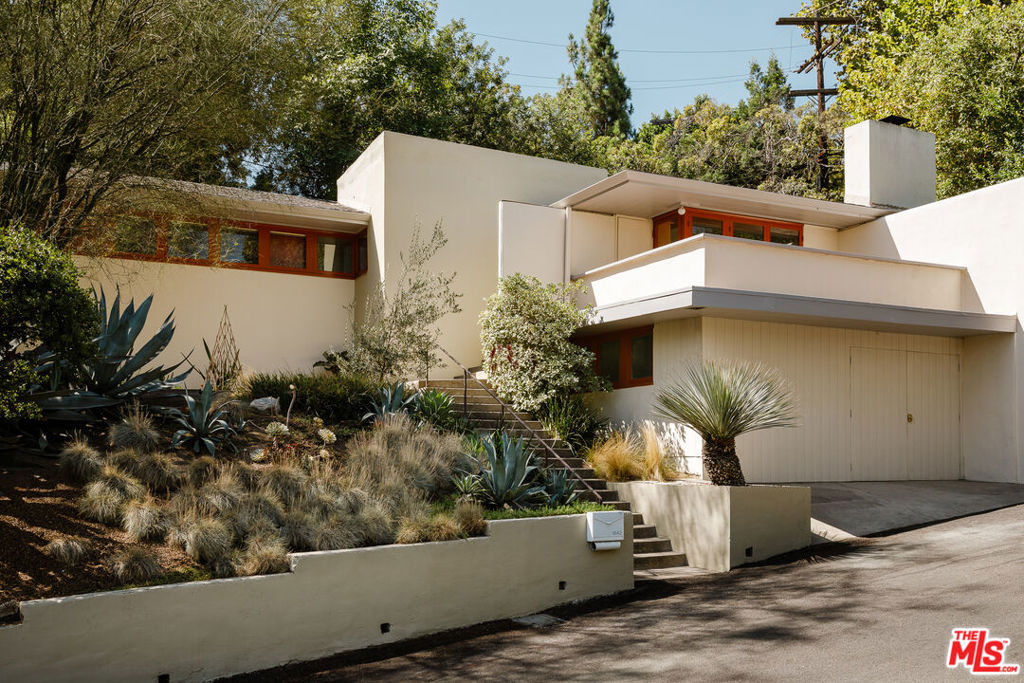 The Laing House | Harwell Hamilton Harris, 1935. The architect's second built home, which came after he had spent several formative years in the office of Richard Neutra. One of the many things he learned there was the importance of the module, having witnessed Neutra's design and assembling of the Lovell Health House. Harris found that he could create harmony and rhythmic patterns working within a modular system, and did so with great effect here and throughout his career. It was the work of Frank Lloyd Wright however that had sent him down the path toward architecture- the seeds having been planted by a visit to the Hollyhock House years prior. It can be seen at the Laing home, with its stucco walls, broad eaves, ribbon windows, and boxed-in balcony. Designed for Caltech professor Graham Laing and his wife, not only as a home but also as a suitable space for him to lecture 25-30 students and store volumes of books. Stepping up from the street, the one-story home consists of two distinct volumes, separated at the entrance. The house reveals the centerpiece of its design after a sharp 90-degree turn from the entrance- an 18 by 30 foot living and dining room with glass paneled doors that swing open at both corners of the room. This grand central room doubles as the professor's lecture hall. To the northeast, a front balcony expands outward towards breathtaking views of the San Gabriel Mountains. In the southwest corner, doors open to the adjacent patio and gardens. A bookshelf wraps the corner ending at the fireplace hearth. The well organized kitchen is adjacent, with a vast countertop placed below a south facing band of windows. Both guest and primary bedrooms include entire south facings of glass doors that open to the rear yard. Throughout the home- original windows, doors, cabinetry, hardware, and light fixtures remain for the most part remarkably intact. Spaces of the home unfold into each other in such a way that makes each room feel part of another, and much larger than its measurement would suggest. Privacy and natural light are provided for in abundance throughout. The original garden plan was composed of California native plants, and was devised in consultation with Theodore Payne. Situated within Pasadena's Poppy Peak historic district, making it an excellent candidate for the Mills Act program and its potential property tax savings.