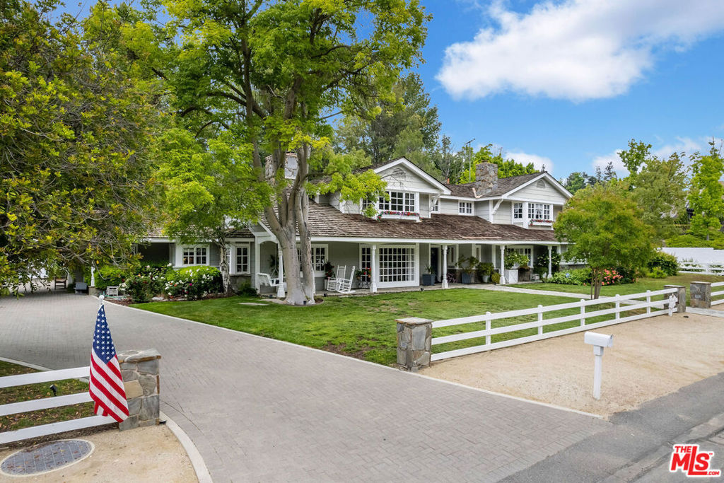Timeless Cape Cod Estate in Prestigious Hidden Hills. Nestled on a quiet double cul-de-sac, this exquisite Cape Cod-style estate offers privacy, security, and a coveted location in one of Hidden Hills' most desirable streets. Thoughtfully designed with sophisticated living spaces and exceptional craftsmanship, the home features a separate guesthouse, game room/music studio, and private gym, making it a true retreat. The principal residence boasts five bedrooms, including two primary suites, one on the main level each, with spa-inspired baths and generous closet space. The well-appointed chef's kitchen showcases a large center island, professional stainless steel appliances, and an adjoining breakfast room with dual wine refrigerators. Designed for intimate gatherings and large-scale entertaining, the expansive great room features a fireplace, wet bar, and large-screen TV, with French doors and oversized windows framing views of the lush surroundings. Outdoors, the resort-style grounds are designed for relaxation and entertainment, with a sparkling pool and spa, built-in BBQ center with bar and gas fire pits, stone patios, and a green lawns. The newly designed 700 sq. ft. guesthouse is a private sanctuary featuring an elegant kitchen with like-new appliances, a spacious bedroom with ample closet space, a designer-finished bathroom, and a newer washer and dryer ideal for guests or extended stays. Set within the guard-gated Hidden Hills community, this estate offers unparalleled luxury, comfort, and timeless charm, a rare opportunity in one of Southern California's most exclusive enclaves.