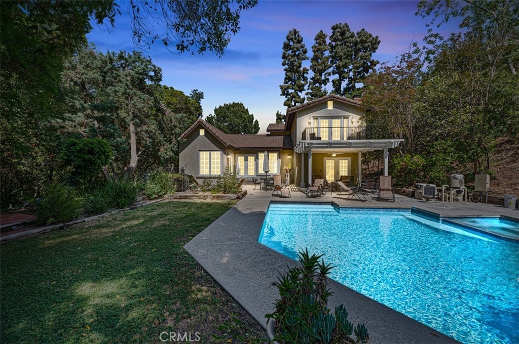 Extraordinarily private estate home situated on a huge lot perched atop a long private driveway at the end of a cul-de-sac in the highly desirable neighborhood of Covina Heights. This home features a pebble-finish pool and spa that were recently remodeled, a huge lot that may be perfect for an attached or detached ADU, and setbacks/elevations that provide maximum privacy. The interior of the home is bathed in natural light via double French doors with sidelights in the family room, dining room, breakfast nook, downstairs bedroom, and primary suite as well as an abundance of near-floor-to-ceiling windows. The main living area opens up to a newly constructed covered patio with a deck on top that is accessible from the primary suite. The formal living room adjacent to the foyer may be ideal for use as an office or possible 5th bedroom conversion. The downstairs bedroom has a separate exterior entrance and direct access to the backyard with a 3/4 bathroom located next to it. The large step-down family room features a fireplace, wet bar, and direct access to the resort-like backyard complete with extensive hardscaping, manicured lawns, gas firepit, and even its own mini "forest" of trees that adds to the tranquility and utmost privacy of this unique estate home!