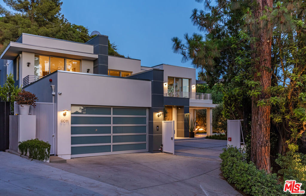 Tucked behind private gates on coveted Alto Cedro Drive, this 5,872-square-foot estate is a study in contemporary elegance. Reimagined in 2022, the six-bedroom, seven-and-a-half-bath residence balances bold modern design with the warmth of enduring materials. Sculptural oak accents, honed marble surfaces, and tailored finishes bring effortless sophistication to every corner, while oversized windows and skylights flood the interiors with natural light and frame tranquil views of the surrounding hills. The grand entry unfolds into an expansive open-concept living and dining space anchored by an architectural fireplace, designed equally for quiet evenings and chic gatherings. Sliding doors blur the boundary between inside and out, leading to lush gardens, a sparkling pool and spa, and multiple zones for outdoor lounging and entertaining. At the heart of the home, the kitchen is a sleek yet soulful showpiece: Calacatta marble countertops, an oversized island, premium appliances, and a seamless flow into the sunlit family room. Pocket doors open to an al fresco dining pavilion, merging form with function in quintessential California style. The main level hosts a serene office with ensuite bath and three spacious guest suites, each with soaring ceilings and abundant natural light. Upstairs, the primary suite is a private sanctuary with sweeping views, a spa-inspired bath wrapped in marble and warm wood, a generous terrace, and a boutique-worthy walk-in closet. Also on the upper level: a plush screening room, two additional guest suites, and a fully equipped gym. Outside, the experience is both Zen and glamorous with a firepit lounge beside the pool, citrus trees perfuming the air and a tranquil pavilion ideal for meditation or conversation. Tech-forward and future-ready, the home includes a Savant smart system, dual EV chargers, solar panels, a backup generator, custom wine storage and an Oxygen Ozone water filtration system. A two-car garage completes the offering. Thoughtfully reimagined for modern life, this Alto Cedro estate blends architectural sophistication with smart technology, wellness-minded amenities and seamless indoor-outdoor flow. With its rare combination of scale, style, and serenity, it offers a compelling vision of contemporary California living at its best, private, polished and undeniably refined.
