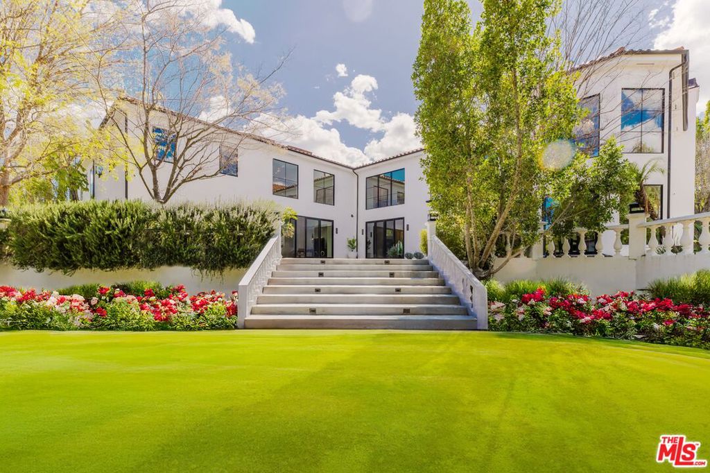 Located in the prestigious, gated community of Hidden Hills West, this fully remodeled estate spans 2.58 acres and offers a rare blend of privacy, luxury, and modern living. With 6 bedrooms, 5.5 bathrooms, and 11,120 square feet of living space, this home is designed to impress at every turn. As you approach, a long gated private driveway leads to a massive motor court, setting the stage for a grand entry. The oversized wooden pivot door opens to a dramatic foyer with a sweeping spiral staircase, inviting you into the heart of the home. Expansive glass doors throughout allow natural light to flood the interior, creating a seamless connection between the indoors and the surrounding landscape. The chef's kitchen is a showstopper, with an oversized marble island featuring waterfall edges crafted from just two large pieces of book matched marble. The kitchen's chevron parquet wood floors flow effortlessly into the formal dining room, where pendant ring-shaped lighting adds an elegant touch. Top-of-the-line Miele appliances and Sub-Zero refrigerators make this space perfect for both everyday living and entertaining. The family room, with its soaring double-height ceilings and oversized windows, is flooded with light. For those who enjoy wine, a beautifully designed wine storage area and bar offer an elegant spot for entertaining guests. Upstairs, the expansive primary suite offers a luxurious retreat. The suite features two sitting area with a dual-sided fireplace, a private balcony with sweeping views of the lush backyard, and elegant chandeliers that enhance the room's sophisticated ambiance. The oversized primary bathroom includes a walk-in shower and steam room, along with a brand-new infrared sauna. The walk-in closet is a standout, with a massive center island for accessories and ample space for storage, including a dedicated area for shoes. A spacious junior primary suite provides a private living room and an en-suite bathroom, offering additional privacy and comfort. The upstairs office is designed to evoke the elegance of a Soho House, complete with a marble fireplace and a grand chandelier wrapped in gold leaf perfect for work or relaxation. The lower level of the home features a guest bedroom with an en-suite bathroom, a butler's kitchen, and a large living room with direct access to a piano entertainment room. Expansive glass doors lead out to the backyard, where the possibilities are endless for outdoor living and entertaining.The estate features a sprawling backyard with a custom pool and beautifully landscaped gardens, creating the perfect setting for outdoor relaxation and entertainment. Gated with secure code entry, this home ensures both privacy and peace of mind. It's a rare opportunity to experience luxurious living at its finest.