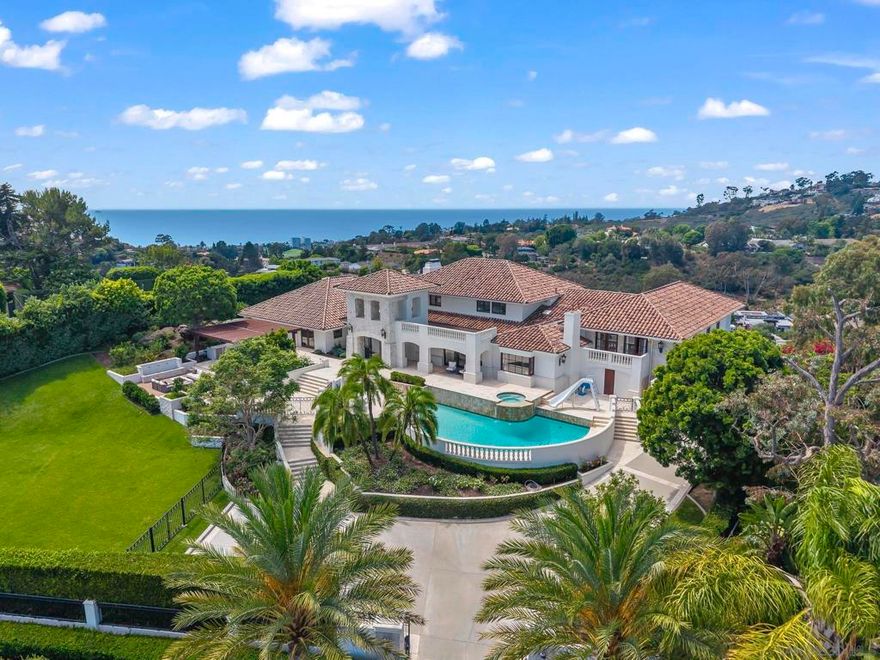 This iconic La Jolla landmark celebrates panoramic sea, sunset, and hillside views from its unique mountainside perspective, and offers an extreme level of luxury and security with vast square footage, magnificent grounds, and an easy access, prestigious hilltop location.   Classic architecture has been appointed with modern design elements for a sophisticated aesthetic throughout, easily adapted to your own curated interior furnishings and style. The sleek SieMatic kitchen opens through disappearing doors for dining al fresco while the opposite side of the property offers fantastic outdoor kitchen, barbecue, and gathering areas and expansive lawns, ready for entertaining on an intimate or grand scale. Secondary suites are on the upper level along with a huge recreation room with spectacular views of the picturesque surroundings. With plenty of room for family and friends, this grand residence offers a gracious and warm welcome to all.  Magnificent modern updates include a top-of-the-line Siematic kitchen with steam oven. Enjoy indoor/outdoor living with four fireplaces inside, (including the vast upstairs recreation/game room,)  and inviting fireplace seating in the private backyard. Welcome guests with plenty of parking within the gates and numerous areas for grand or intimate gatherings. A very special private estate in a picturesque, easy-access setting.