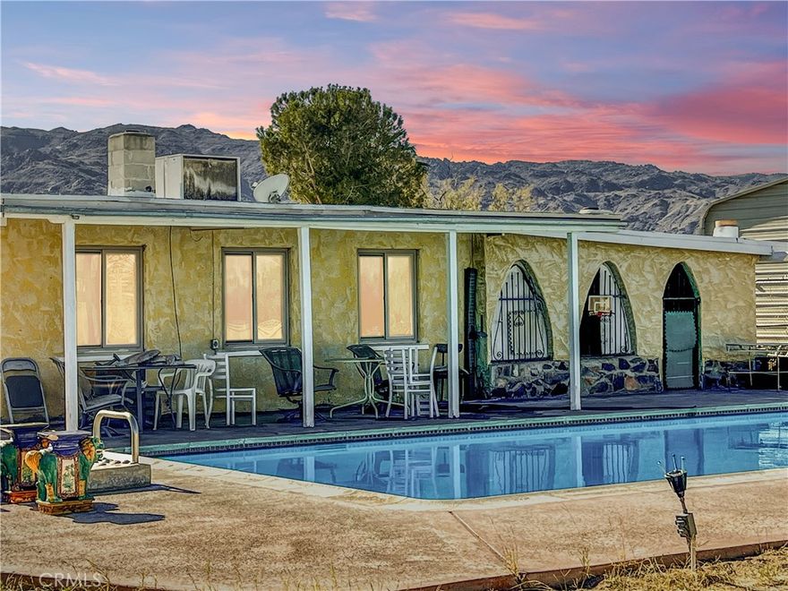 Welcome to 74284 El Paseo Dr. in 29 Palms, a spacious three-bedroom, two-bath pool home offering approximately 1,788 square feet on an expansive 1.25-acre lot. While the home could benefit from some light TLC, it already has a strong foundation of desirable features, including all-tile flooring for easy maintenance and updated dual-pane windows throughout. Two bedrooms and one bathroom sit on one side of the home, while the opposite wing offers a unique oversized bedroom suite that could be used as-is or potentially reconfigured into two smaller bedrooms with a living area—an excellent option for those needing flexible space. The kitchen includes upgraded stainless steel appliances, and the home offers multiple heating options with a pellet stove, wood-burning stove, and central HVAC on the opposite side. The impressive wood-beam ceilings highlight craftsmanship that’s becoming rare to find. Outside, you’ll find a fantastic in-ground pool, a covered patio, and a fully walled backyard for privacy. A standout amenity is the huge workshop/garage equipped with 220V power, dual oversized roll-up doors, and approximately 1,200 square feet of space, plus an additional carport with a solid foundation. For buyers with recreational vehicles, tools, or equipment, this setup is exceptional. Additionally, the home next door—and the connecting lot beside it—will also be available, creating the potential opportunity to assemble a multi-property family compound. With a little polish, this home is a true diamond in the rough offering space, utility, and tremendous potential.