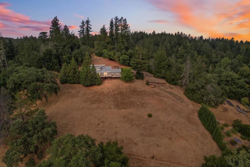 Tucked away in the mountains, this spectacular home recently received numerous upgrades, including newly installed carpeting, fresh interior and exterior paint, stylish contemporary fixtures, refreshed kitchen countertops, and a restructured deck for added safety and enjoyment. The west-facing deck is a showstopperoffering sweeping views of mountain ridgetops and brilliant sunsets, the ideal spot to relax with a glass of wine as the stars begin to sparkle overhead. Inside, an open-concept layout connects the kitchen and living room, so you can stay part of the conversation while preparing a meal. The living room boasts soaring ceilings with clerestory windows that flood the space with light, plus a cozy fireplace perfect for cool mountain evenings. Garden enthusiasts will appreciate the space to grow their own fruits and vegetables. Conveniently located near major commuter routes, the beloved Sawmill restaurant, and the charming shops and cafes of downtown Boulder Creek.