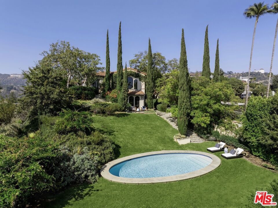 This restored Spanish villa sits on a large promontory offering sweeping views from the city to the ocean. It combines modern amenities with the timeless character of its original period design. A gracious wood beamed rotunda entrance, a soaring vaulted truss ceiling in the living room, large picture windows, French doors with original carved arches, rich wood flooring and Malibu tile accents throughout are just a few of the home's striking design features. The floor plan features a center-island kitchen, wood-paneled office, family/media room, formal living room with a bar and fireplace, formal dining room, and two powder rooms. An interior circular stairwell leads to a spectacular guest suite with a private exterior entrance, an elegant bathroom, and a separate sitting room with a kitchenette. The exquisite grounds include an inner courtyard, multiple patios, an expansive lawn, and a striking swimming pool, all set within a secluded cul-de-sac in The Oaks community.