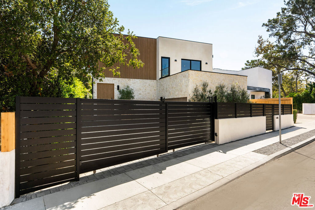 Organic Modern Meets Mediterranean Luxury in this Custom Architectural Masterpiece. This gated, custom-built 6-bedroom, 5-bathroom Brentwood estate with a pool, spa, rooftop deck, and home theater blends the warmth of European influences with the elegance of organic modern architecture. Every inch is designer-curated, from hand-selected natural materials to bespoke finishes. Step through the impressive 11-foot oak pivot door into a dramatic double-height foyer, enhanced by LED wall accents, two oversized skylights, and glass railings flanking the sculptural floating staircaseall leading to serene backyard views. The spacious open-concept layout flows seamlessly into a chef's kitchen with top-of-the-line appliances, push-to-open walnut cabinetry, and richly textured Taj Mahal countertops in a rare leathered finish an earthy yet refined statement. The oversized kitchen island seats eight. A second kitchen blends function and luxury, featuring a pantry, wet bar, dry-goods storage, and a dedicated drink station with built-in microwave and beverage refrigerator - perfect for entertaining or multi-generational living. Whether prepping for a party, grabbing a snack, making cappuccinos, or mixing cocktails, this space is as stylish as it is practical. Wide plank oak flooring flows throughout the main living areas, while luxurious limestone enhances each bathroom with a timeless, organic feel. Two massive 20-foot sliders open to an expansive yard with a generous deck, outdoor kitchen, and glimmering pool - perfect for al fresco dining and entertaining. The oversized driveway accommodates up to four vehicles in addition to a 2 car garage pre-wired for EV charging. Downstairs includes 2 bedrooms and 2 bathrooms - ideal for guests or a lifestyle wing with a private home theater, gym, office, and a convenient mudroom off the garage. The luxurious primary suite offers a resort-style experience with a custom walk-in closet, spa-inspired bathroom, and oversized balcony. Floor-to-ceiling glass walls frame views of the lush, secluded backyard oasis, where mature landscaping and limestone finishes evoke total tranquility. Designed for unforgettable outdoor living, the yard includes a custom BBQ area and a sparkling pool with integrated jacuzzi. This smart home is pre-wired with Cat 6 high-speed internet, whole-house audio, surround sound and projector in the theater, rooftop projector, and three-zone climate control. The second floor features 4 bedrooms, 3 bathrooms, and over 700 sq ft of outdoor patio space. An upstairs laundry room adds convenience. Atop it all, a 2,000 sq ft rooftop deck offers panoramic views from the Santa Monica Mountains to DTLA, with the Getty in clear sight. Whether hosting a sunset gathering or enjoying quiet morning yoga, the space invites you to live elevated. Located in a prime Brentwood neighborhood, just moments from top restaurants, shops, cafes, and the Brentwood Farmers Market. This rare architectural gem won't last long - an ultimate retreat for elevated living.