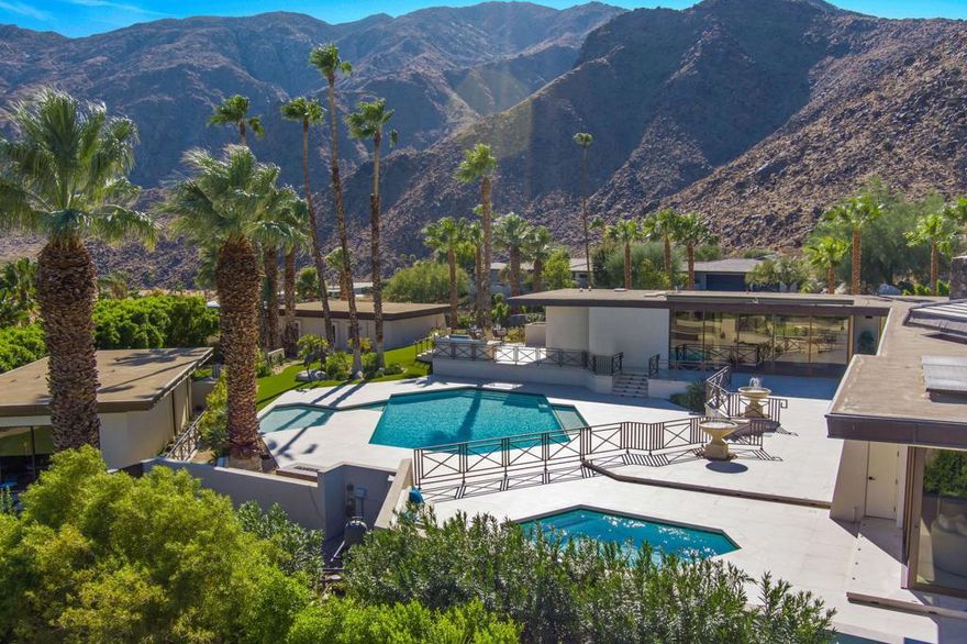 Serenely nestled within the private gated Rose Hill enclave of Las Palmas Heights sits an iconic residence, steeped in history, and displaying the epitome of timeless architectural glamour. Situated at one of the most scenic points in Palm Springs, this Buff & Hensman designed masterpiece was originally built for Jerry Zarowitz, of Caesar's Palace, and has been thoughtfully upgraded for today's technological and aesthetic tastes. Celebrities such as Frank Sinatra and friends have enjoyed the breathtaking views and complete privacy afforded within gated confines of the over 1.31ac Estate. Fast forward through 5 years of major restoration & addition with the Designer's uncompromising efforts to restore & authenticate a 1972 home to today's expectations while maintaining the property's bold architectural significance. The research & execution of the transformation is truly remarkable & will be appreciated by an aficionado of a classic property. The exquisite nature of each space is evident from the fully reimagined Primary suite; 3 guest suites; media room/office; formal dining w/custom floating 3-sided wine cellar; gourmet kitchen; sunken living room; fully equipped wet bar; new 1 bedroom guesthouse w/full kitchenette; putting green; 3 car garage w/catering kitchen. Offered 'Turnkey Furnished' (look at 'Documents' for Notable Pieces and More). Solar Lease.