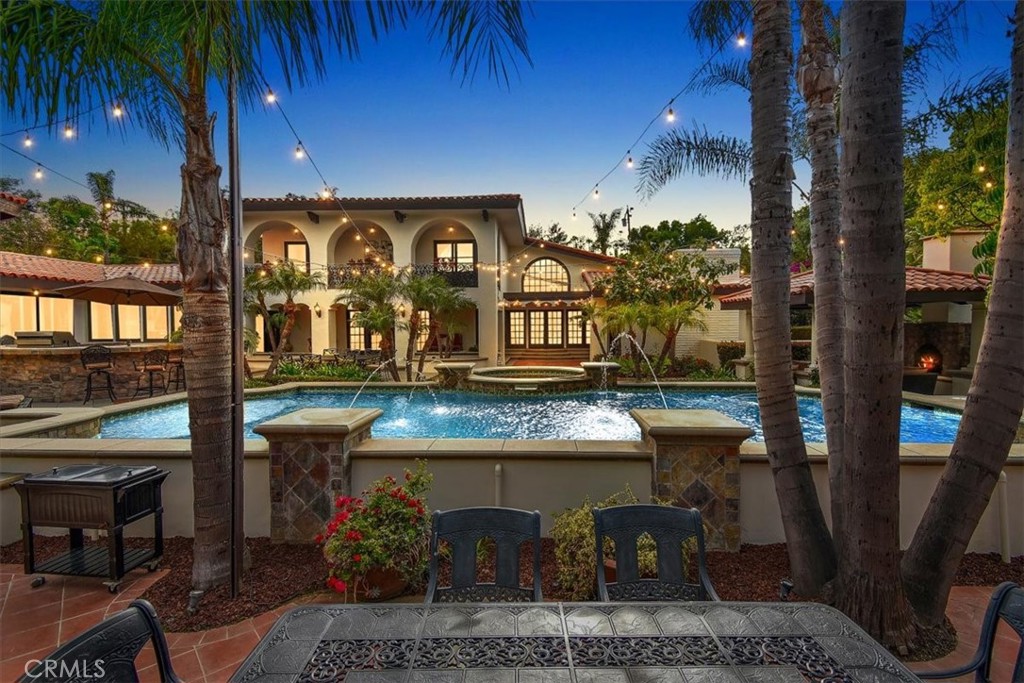 Welcome to your own private Mediterranean-inspired retreat, tucked behind gates on a peaceful cul-de-sac in the coveted community of Orange Park Acres. This extraordinary estate spans over 6,500 square feet and sits on nearly an acre of beautifully landscaped grounds, offering the perfect blend of luxury, comfort, and everyday function. Featuring 5 spacious bedrooms and 7 elegant bathrooms, the home is a true sanctuary designed for privacy, relaxation, and entertaining. As you enter through a grand porte-cochère and into the dramatic courtyard, you're welcomed by timeless architectural charm and refined interior finishes. The remodeled custom kitchen includes a massive center island, stacked stone fireplace, and high-end appliances—ideal for both casual living and hosting. A formal dining room with French doors opens to the backyard, seamlessly blending indoor and outdoor spaces. Additional highlights include a spacious family room with a stunning glass-walled rotunda, an executive office, and remodeled bathrooms with rich stone finishes. The luxurious primary suite is a peaceful escape with a jetted tub, oversized walk-in stone shower, and ample closet space. Throughout the home, you'll find wood and stone flooring, plantation shutters, beamed ceilings, and designer lighting that create an atmosphere of timeless sophistication. Outside, resort-style amenities await. Enjoy a sparkling saltwater pool with a Baja bench, an entertainer’s loggia, built-in BBQ center with bar, two outdoor TVs, and a Bluetooth surround sound system. A putting green and covered patio with stone fireplace complete the space, while a sprawling grass area offers room for recreation or future enhancements. Nature lovers will appreciate the fruit trees and tranquil garden area—ideal for reading, relaxing, or simply enjoying the serene surroundings. A secluded basement room provides a quiet retreat or creative studio. The estate also features an oversized four-car garage and circular drive with space for guests, RVs, or boat parking. With its prime location, high-end finishes, and resort-like grounds, this is a rare opportunity to experience the best of Orange Park Acres.