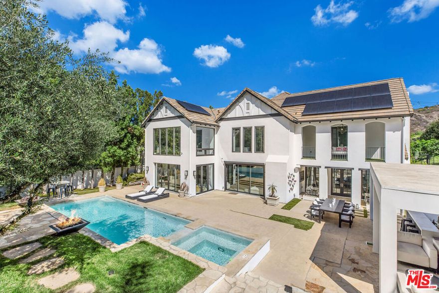 Situated on a coveted corner lot in the exclusive gated community of The Oaks, this stunning estate offers unparalleled privacy and luxury living. Spanning expansive wrap-around acreage, recently updated park-like landscaping and unmatched appeal, the property boasts exceptional outdoor features including a private sport court and a resort-style pool and spa. The outdoor entertaining area includes a covered lounge with a BBQ bar, as well as elevated hillside seating areas, offering a secluded retreat perfect for relaxation and entertaining. Inside, the home exudes stylish sophistication with a modern artistic flair. The expansive family room features a custom modern fireplace and seamlessly flows into a state-of-the-art kitchen, complete with a waterfall stone island bar and striking backsplash. A custom-designed entertaining bar lounge and tasting area further enhance the home's appeal for hosting. A thoughtfully designed kids' lounge is equipped with a fridge, play area, storage, and entertainment space, providing the perfect environment for family living. The lower level also includes a private-entry en suite bedroom, ideal for guests or extended family.The home's state-of-the-art theater room offers a custom cinematic experience, while the second level features four beautifully designed en suite bedrooms, each with unique styling. A cozy living room lounge and a private gym with floor-to-ceiling windows overlooking lush greenery add to the estate's appeal. The primary suite is a luxurious retreat, featuring a custom walk-in closet with accent lighting and a spa-like bathroom with double vanities, an oversized shower, a walk-in dry sauna, and a private glam space. This modern hideaway embodies sophistication and comfort, offering a rare opportunity to experience life in one of Calabasas' most sought-after neighborhoods.With exceptional amenities, ultimate privacy, and breathtaking views, this estate truly redefines luxury living behind the prestigious guard gates at The Oaks.