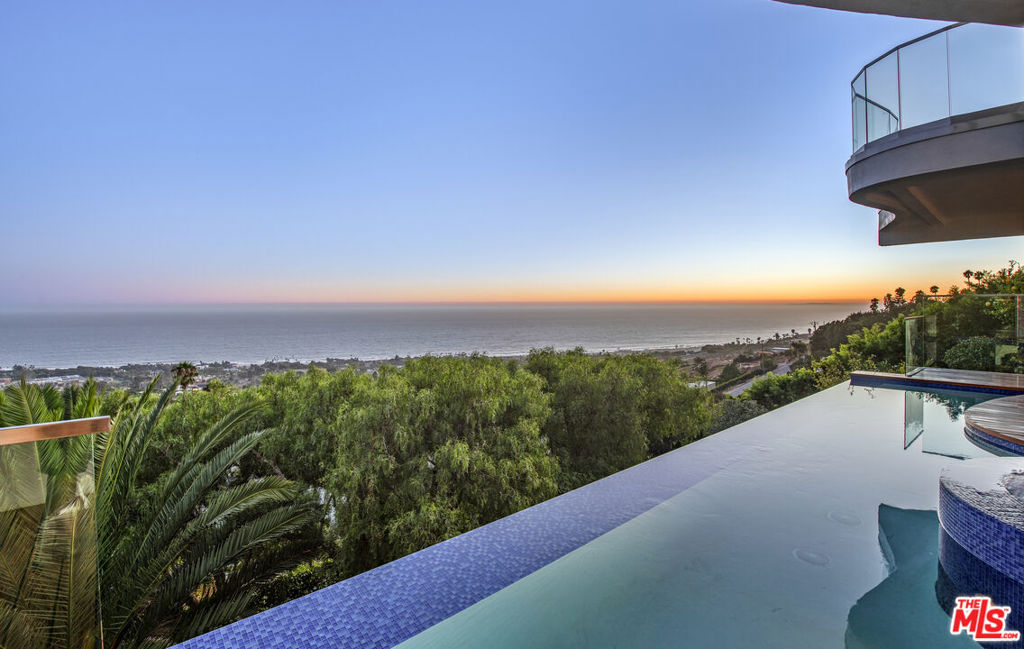 Welcome to a One-of-a-kind entertainer's paradise with unobstructed sunrise and sunset ocean views. Rare opportunity in Malibu Park to own a property that has Primary View Preservation Rights. This spectacular 3 bedroom 3.5 bath residence was extensively and thoughtfully remodeled with custom, high end designer finishes. Enter through stainless steel security gates into a tranquil entrance atrium where you can enjoy the ocean breeze and soothing sounds of a waterfall feature before being greeted by high ceilings, oak floors and spectacular panoramic views. The Gourmet kitchen features premium Dornbracht fixtures, Miele appliances and an outdoor Italian Pizza oven. Two sculptural marble fireplaces and floor to ceiling sliding doors that open up to approximately 2,000 sf of expansive Neolith-clad decks add dimension to the main entertaining level. The media room is complete with surround sound, custom black out curtains, and features a Wine connoisseurs dream: a temperature-controlled jewel of a wine room designed to display 450 bottles. The luxurious Primary suite features an oversized marble fireplace, large closet, motorized blinds, large steam shower and soaking tub with ocean views.An Entertainers' dream on the third level includes a stunning Ipe wood deck and a custom infinity saltwater pool with floating spa, fire pit, bar area, and a gym. The Landscaped, fenced in yard with outdoor lighting, includes a variety of mature fruit trees and flowers.Every detail has been thought of, a multi-zone speaker system, security cameras, Lutron lighting, tank-less water heater, and Halo water filtration system. Minutes from the famous Zuma beach, this one-of-a-kind Masterpiece is not to be missed!