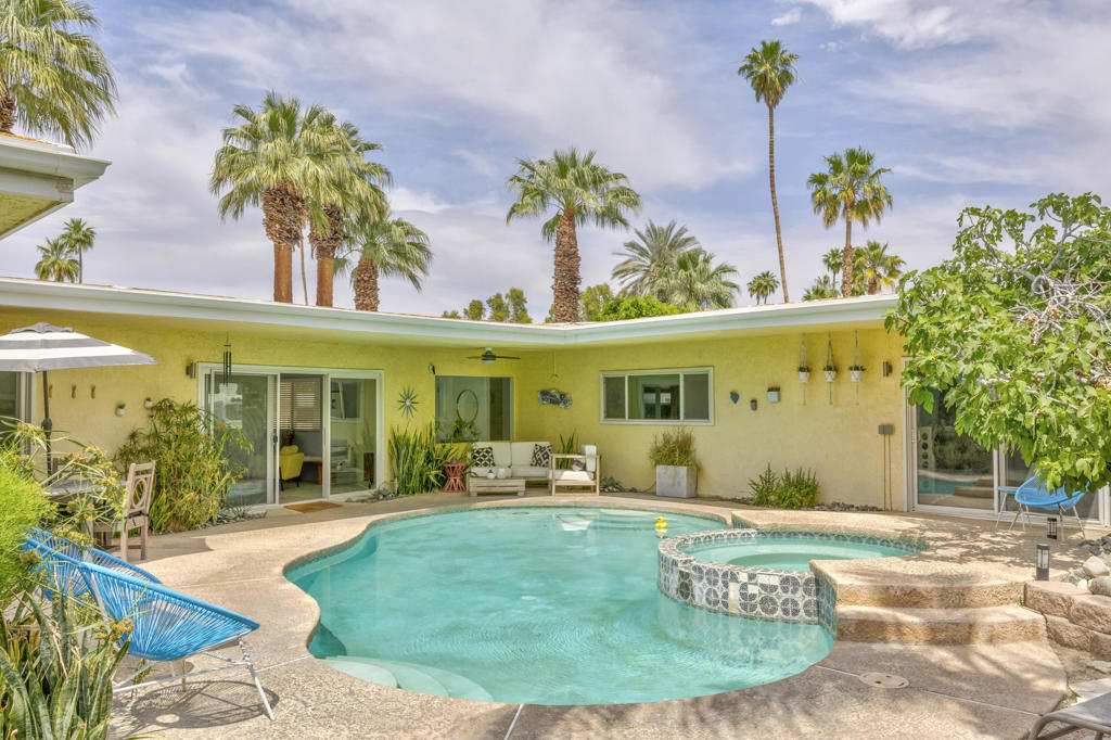 Discover a quintessential mid-century gem that perfectly captures the Palm Springs lifestyle! This move-in-ready fully furnished home offers fantastic curb appeal with minimal landscaping, a sleek flat roof design, and stunning mountain views. The backyard is a true oasis, featuring a sparkling pool, relaxing spa, and a beautiful fig tree, creating the ideal indoor-outdoor living experience. Step inside to find a picture window framing the serene outdoor space, while the living room boasts a classic mid-century fireplace, seamlessly flowing into the kitchen and dining area.The galley kitchen includes updated appliances and a convenient storage room that can double as a pantry. Off the dining area, the primary suite provides private exterior access to the pool for tranquil mornings and evenings. On the opposite side of the home, you'll find a second suite with its own living area or office space and an en-suite bathroom, ensuring privacy and flexibility. A third bedroom, along with a guest bath showcasing original pink tile for an iconic mid-century touch, offers additional accommodations. Located in close proximity to El Paseo's renowned shopping and dining, as well as the beloved Living Desert Zoo and Gardens, this property combines style and practicality in an unbeatable location. Plus, it's just a short drive to the vibrant offerings of Palm Springs. Whether you're seeking a turnkey residence or a blank canvas to create your mid-century dream, this exceptional home delivers both charm and opportunity!