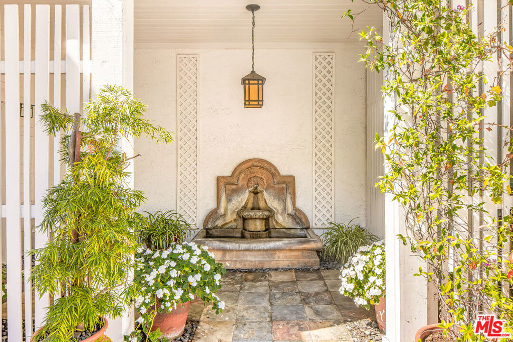 Serene Sanctuary Behind Private Gates in Desirable Beverly Glen. Enter through a secluded gate into a lush courtyard oasis, where mature foliage, vibrant potted blooms, and the tranquil melody of a water fountain set a gracious tone for this refined residence. Ascend from the welcoming foyer, complete with a bespoke cedar-lined coat closet to a sunlit living space graced by soaring ceilings, warm hardwood floors, and elegant double-paned windows framed in rich wood shutters. The open plan invites grand entertaining as easily as tranquil intimate evenings by the piano, with a seamless flow into a charming dining area. Revel in a gourmet kitchen anchored by hand-finished wooden counters and gleaming stainless appliances, custom white cabinetry, and an alcove ceiling that bathes the space in light. Enjoy mornings at the inviting breakfast bar or lose yourself in a cozy nook, perfect for savoring coffee, reading recipes, or quiet contemplation. Storage abounds, and a discreetly housed laundry space offers convenience. The main-level primary suite is awash in serenityairy, bright and beautifully appointed with generous closets, custom built-ins, and a spa-inspired bath featuring a deep soaking tub, glass-enclosed shower, and signature Toto fixtures. A sculptural mezzanine bridge floats above the living room, leading to a grand vaulted-ceiling great room complete with media features and French doors revealing a private yard. Jardin-style landscaping, a canopy of shade, and alfresco seating create a sublime outdoor retreat. Two additional bedrooms, one with a balcony, another with dramatic timber ceilings, open directly to the enchanting yard and share a richly-appointed bath with artisan wood finishes. Discover thoughtful touches throughout: a spacious two-car garage with extra storage, central vacuum, and moments-away access to Beverly Glen Center's acclaimed restaurants, coffee, and entertainment. A rare opportunity to live enveloped in tranquility, sophistication, and inspired design all minutes from both Westside culture and Valley convenience. Note: Dining room, kitchen chandeliers, and silk drapes on the lower level excluded.