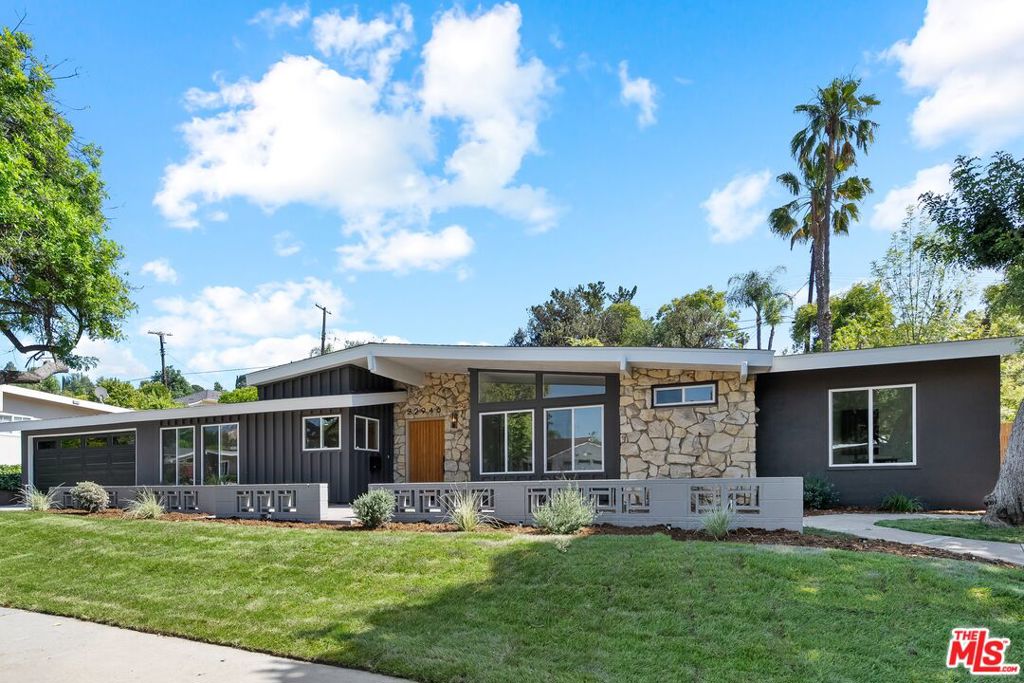 Mid-Century Modern architectural masterpiece by the iconic Charles Du Bois, nestled in the coveted Woodland West neighborhood of Woodland Hills. This single-level home blends the bold geometry, natural textures, and timeless elegance that define Du Bois' coveted work. Thoughtfully revitalized and updated by the award-winning Maverick Design team, this rare gem has been infused with modern charm while preserving its architectural pedigree. A dramatic post-and-beam roofline, expansive clerestory windows, and Du Bois's signature natural stone faade create unforgettable curb appeal. Inside, vaulted ceilings with exposed wood beams and wide-plank engineered wood flooring accentuate the home's airy layout. A slate-tiled foyer leads to the breathtaking living room, anchored by a floor-to-ceiling decorative stone fireplace, exposed beams, and wide sliding glass doors that invite in sunlight and offer direct access to the backyard retreat. The space flows into an open-concept dining area with a sculptural brass chandelier overlooking lush outdoor views. The chef's kitchen is a work of art, featuring a stunning Warmia Walnut center island, Pietra Grey porcelain countertops, modern cabinetry, ceramic tile backsplash, brushed gold finishes, and a full suite of Cafe luxury appliances. A spacious primary suite boasts vaulted ceilings, sliding glass doors to the pool, dual mirrored closets, and a luxurious en-suite bath with artisan subway tile, a glass-enclosed shower, brushed gold finishes, fluted wood double vanity, and Italian porcelain flooring. Three additional bedrooms are bright, spacious, and thoughtfully appointed, each with high ceilings, mirrored closets, and serene views of the backyard or tree-lined street. The hallway bath includes a floating oak vanity with quartz countertops, matte black hardware, an arched mirror, artisanal tile surround, and grey hex porcelain flooring. Outside, a backyard oasis truly feels like a private resort, complete with a sun-drenched sparkling pool, beautiful patio, elegant white pergola, and generous lawn space. Surrounded by lush greenery and mature trees, this serene backyard is perfect for entertaining or peaceful relaxation. Just minutes from Calabasas Commons, farmers markets, scenic hiking trails, and offering easy access to the 101 freeway, premier shopping, dining, and more. THIS IS A MUST SEE!