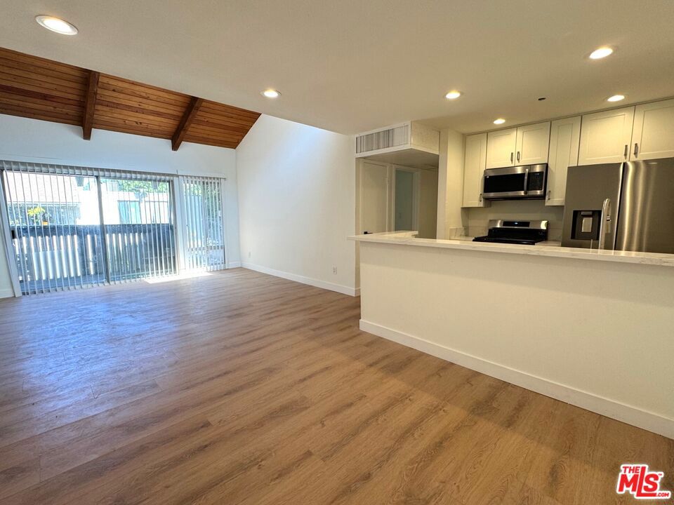 Welcome to this beautifully updated 2-bedroom, 1-bath condo featuring fresh paint, new flooring, and a spacious layout filled with natural light. The living area boasts a soaring vaulted beam ceiling and opens to a lovely, private balcony. The remodeled kitchen includes sleek stainless steel appliances, a breakfast bar, and an adjoining dining space, all seamlessly connected to the main living area. A short hallway leads to two comfortable bedrooms, including the spacious primary bedroom with a walk-in closet. The modern full bathroom has a large vanity, a shower-tub combo, and convenient dual access from both the hallway and the primary bedroom. Nestled in a serene, park-like community surrounded by mature trees, this condo also offers access to great amenities like a pool and clubhouse.