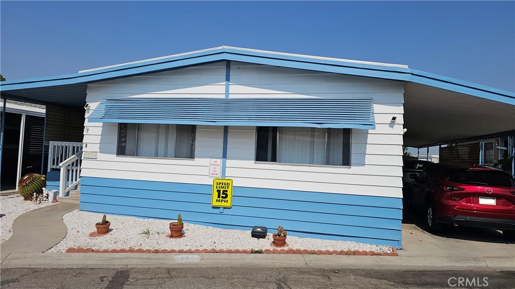 What a fantastic buy. This manufactured home is down the street from LLUMC / VA Hospital, Hospitality Lane and 215/10 Freeways. This is the only current 3 bedroom 2 full bathroom manufactured home available in the community. It comes with a new upgraded kitchen with quartz counter tops and new cabinets. New appliances. All upgraded beautiful HDF hardwood flooring. It has a nice sized dining area. Along with a living room that overlooks the kitchen and dining area. Plus a family room. All 3 bedrooms are well sized rooms. The 2 bathrooms are full bathrooms. You have an indoor laundry room.
Plus a large carport where you can fit 2-3 vehicles. It has great curb appeal. Plus a large front porch and a nice sized back porch for more privacy & star gazing at night. This is a must see unit. The furniture is negotiable as well.